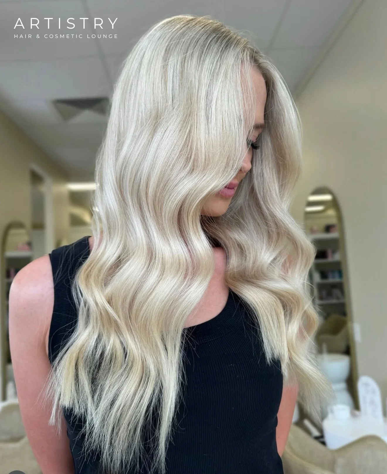 Woman with long, wavy platinum blonde hair in a hair salon.