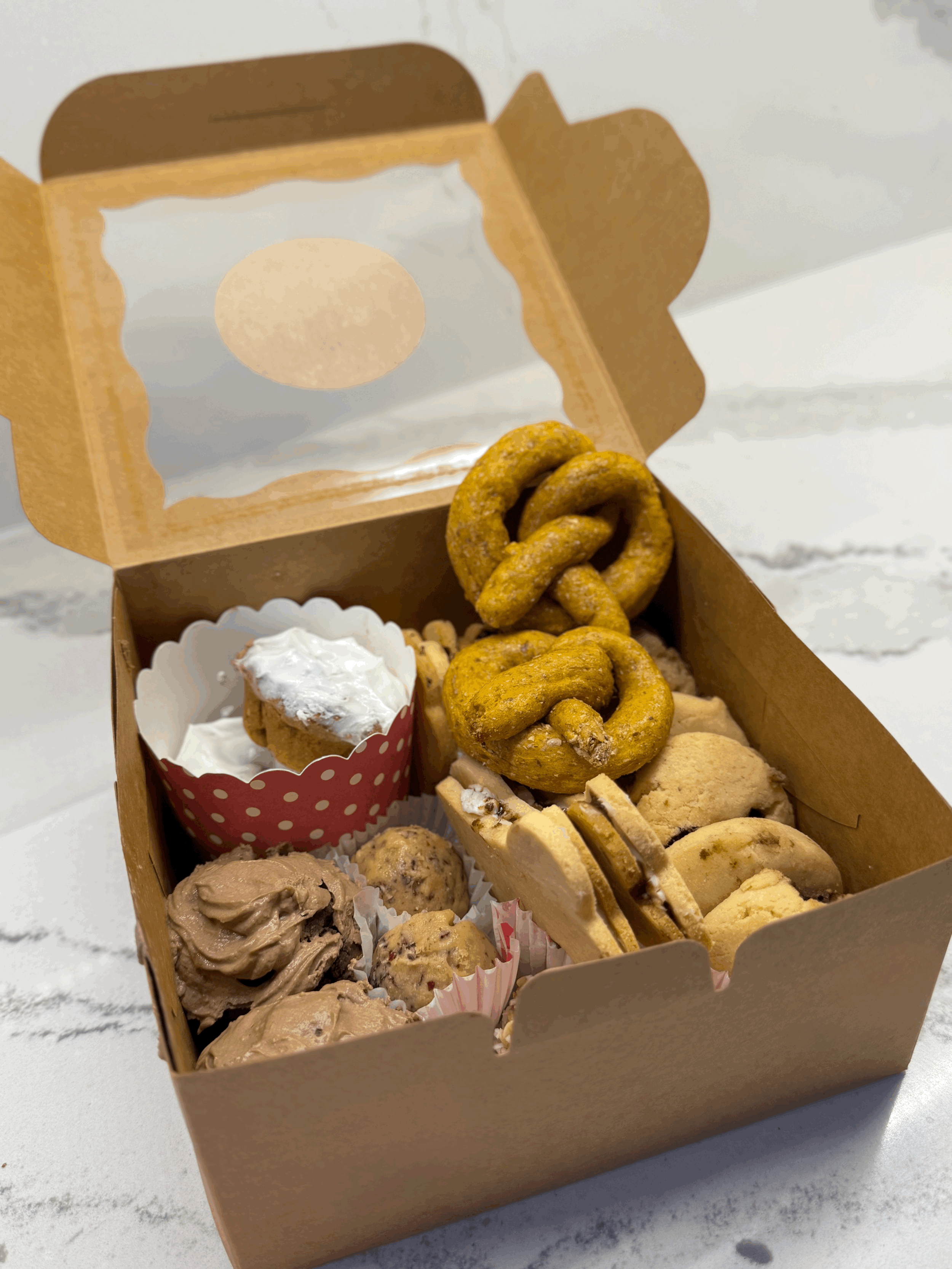 large assorted dog treat box, with cupcakes, cookies, biscuits and more. made with natural and organic products like peanut butter, almond flour, flaxseed, sweet potato and more