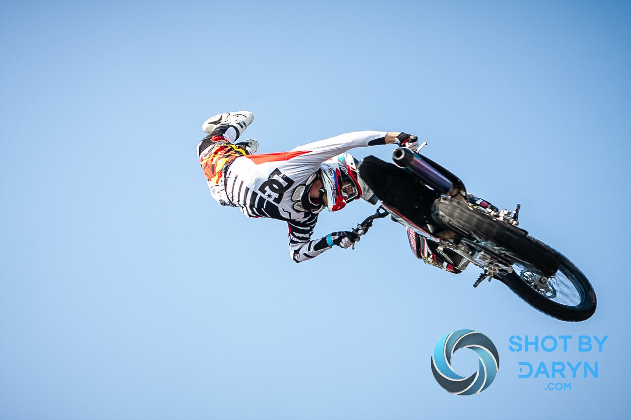 Motocross rider performing an aerial stunt in the sky.
