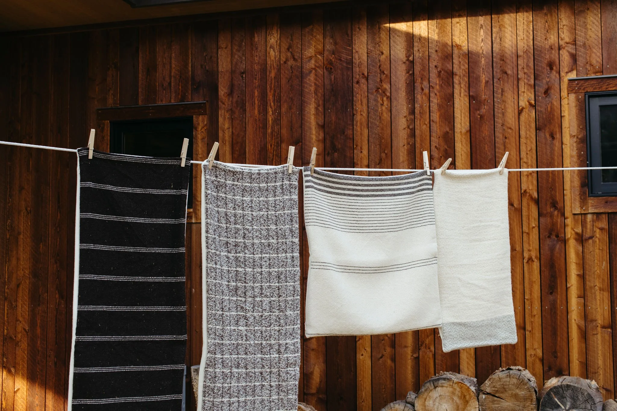 Handwoven Montana wool throw pillows with a geometric pattern hanging from a clothesline to dry.