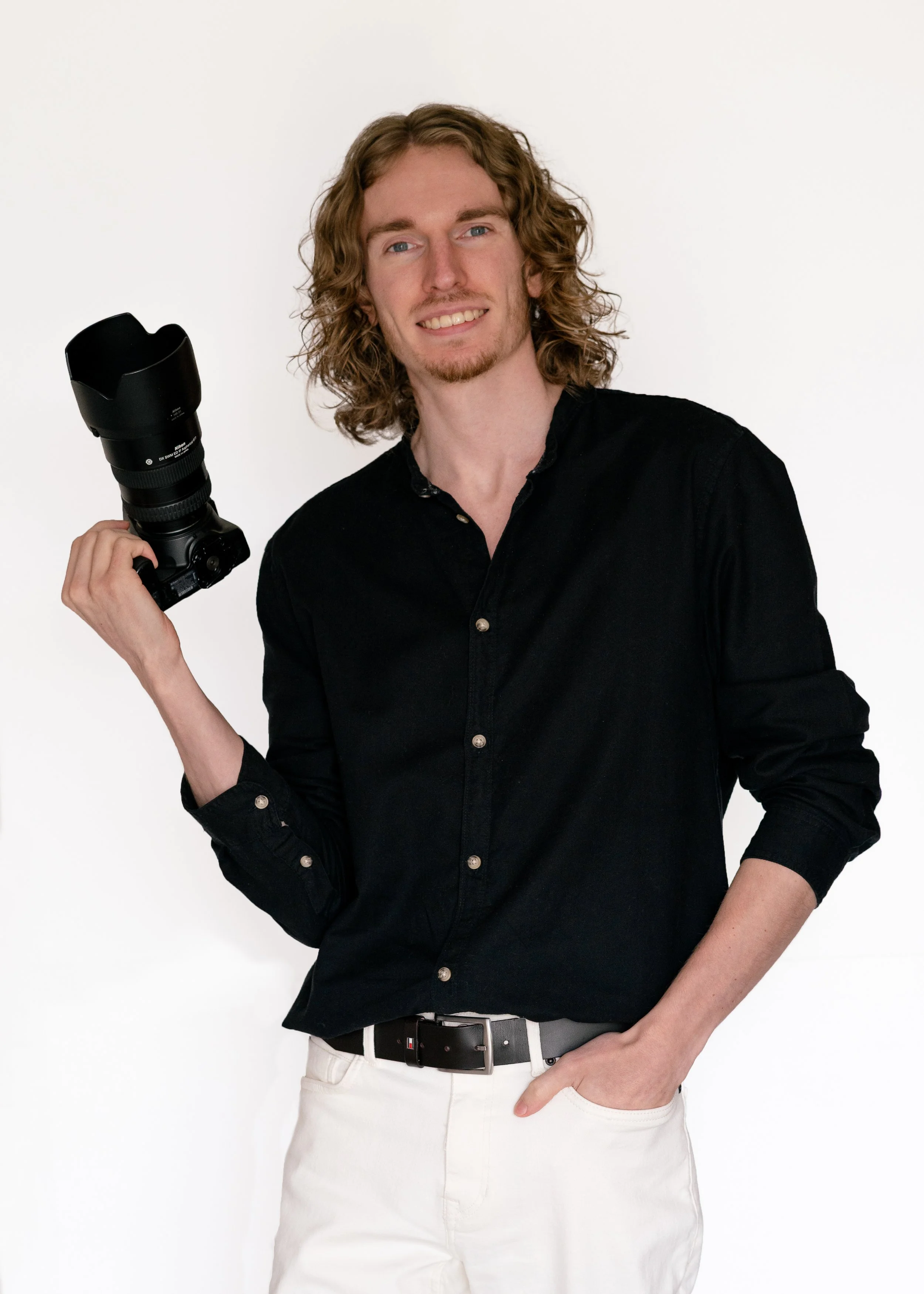 Bonjour, je suis Nicolas Lescouffe. Je suis un homme aux cheveux et bouclés, je pose devant un mur blanc, porte une chemise noire et tiens un appareil photo dans la main. Je suis toujours partant pour de nouveaux projets, alors discutons du vôtre.