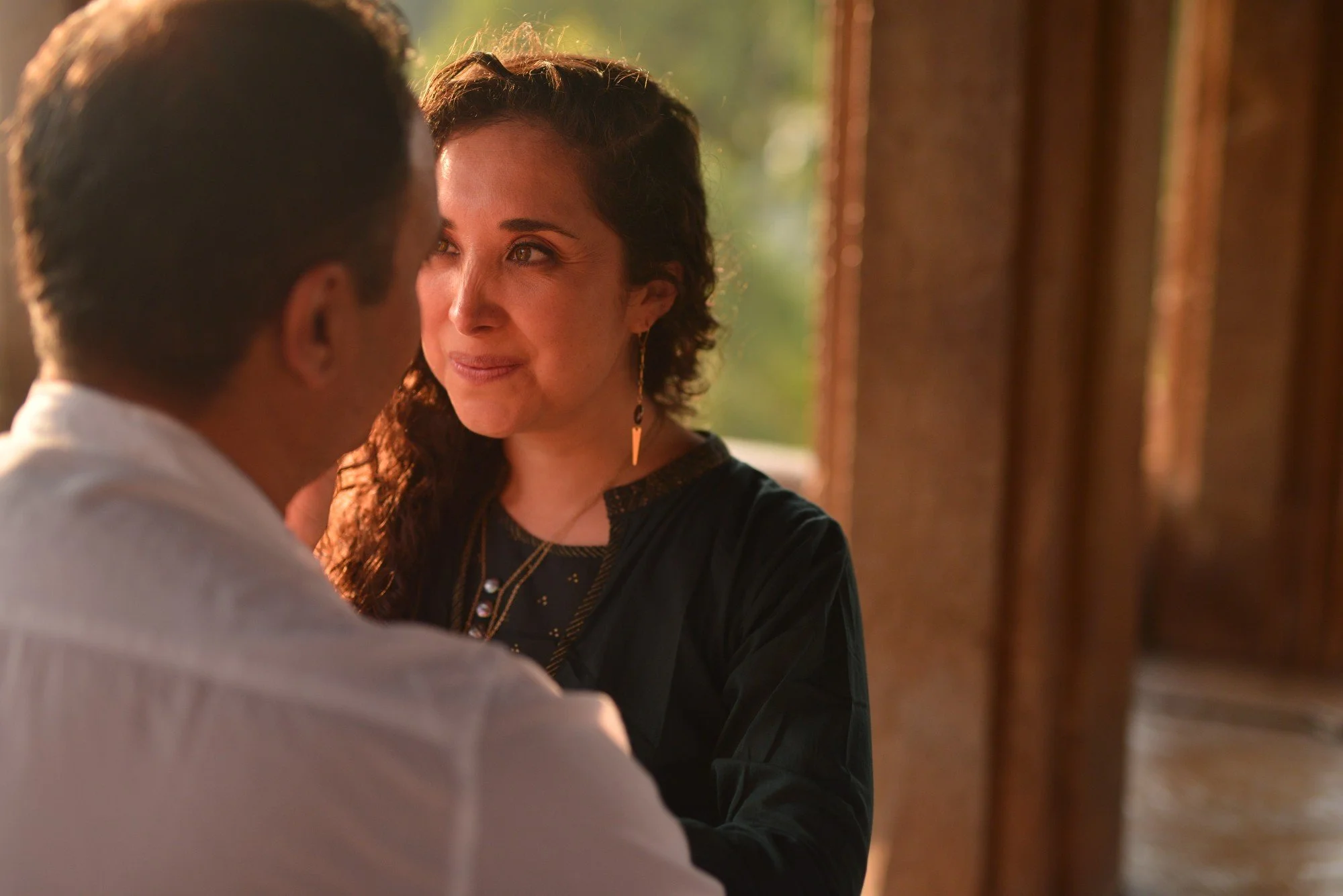 Woman in beige dress wearing layered pearl necklaces and rings