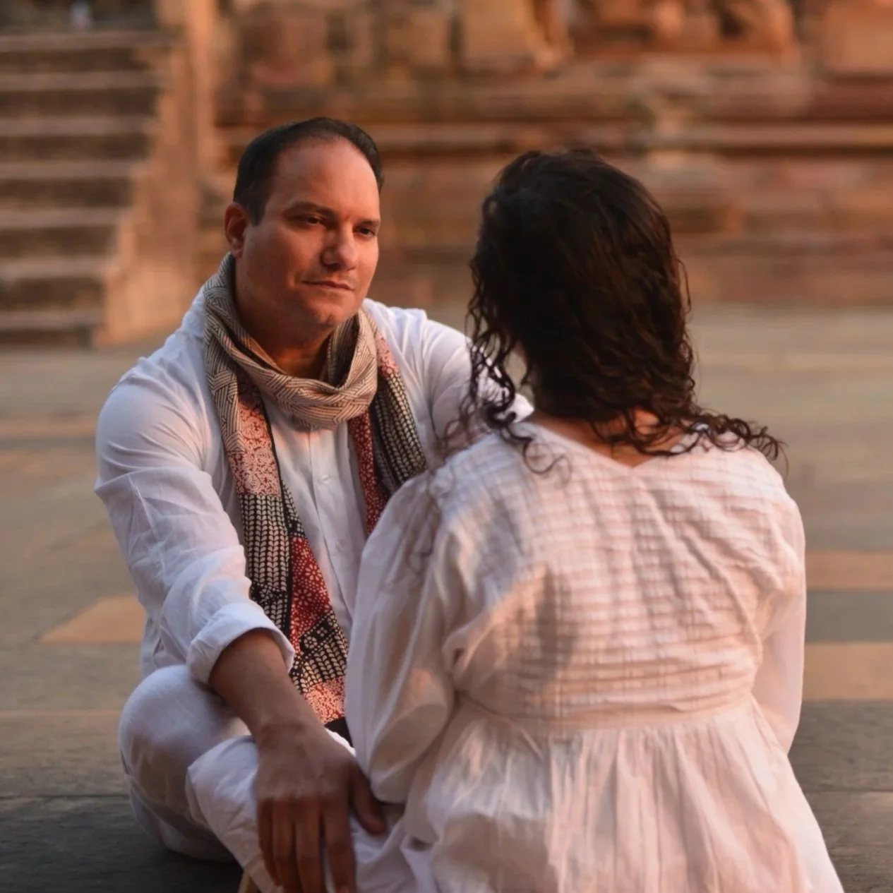 Woman holding a white ceramic bowl with a lit candle, wearing a dress with a floral design.