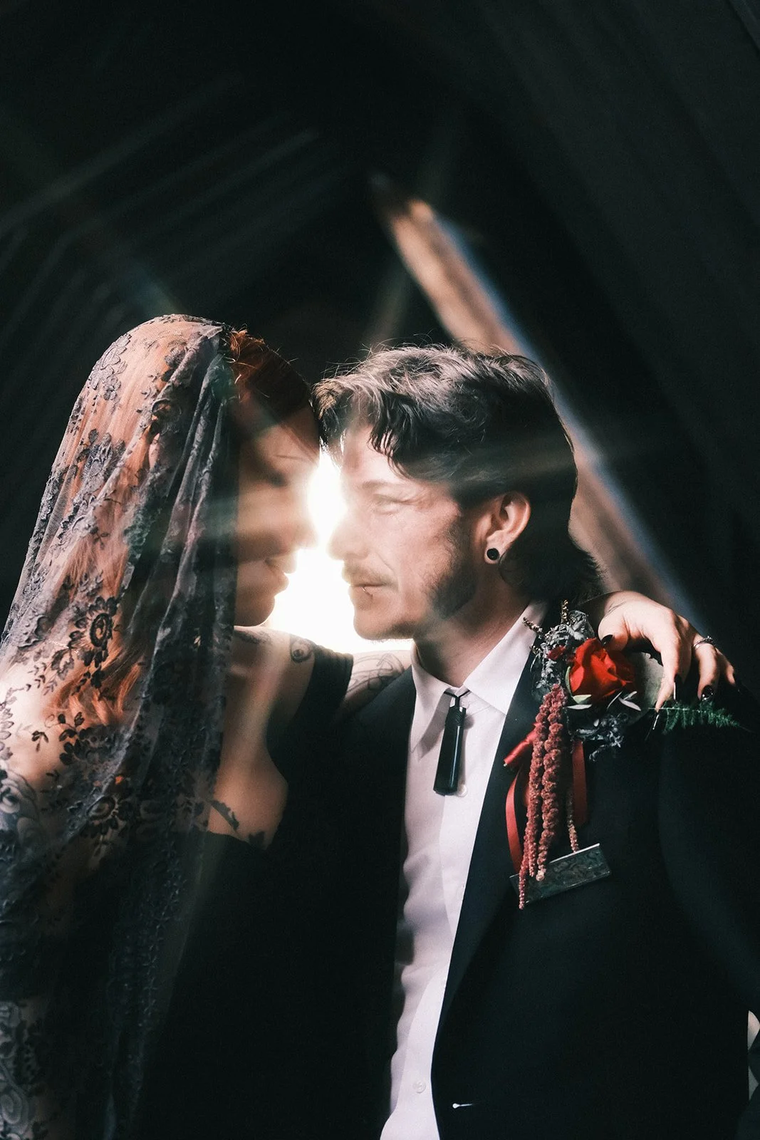 A bride and groom at their wedding at Montsalvat at the Yarra Valley. There's a beam of light in the shape of a star between their faces as they look at each other.