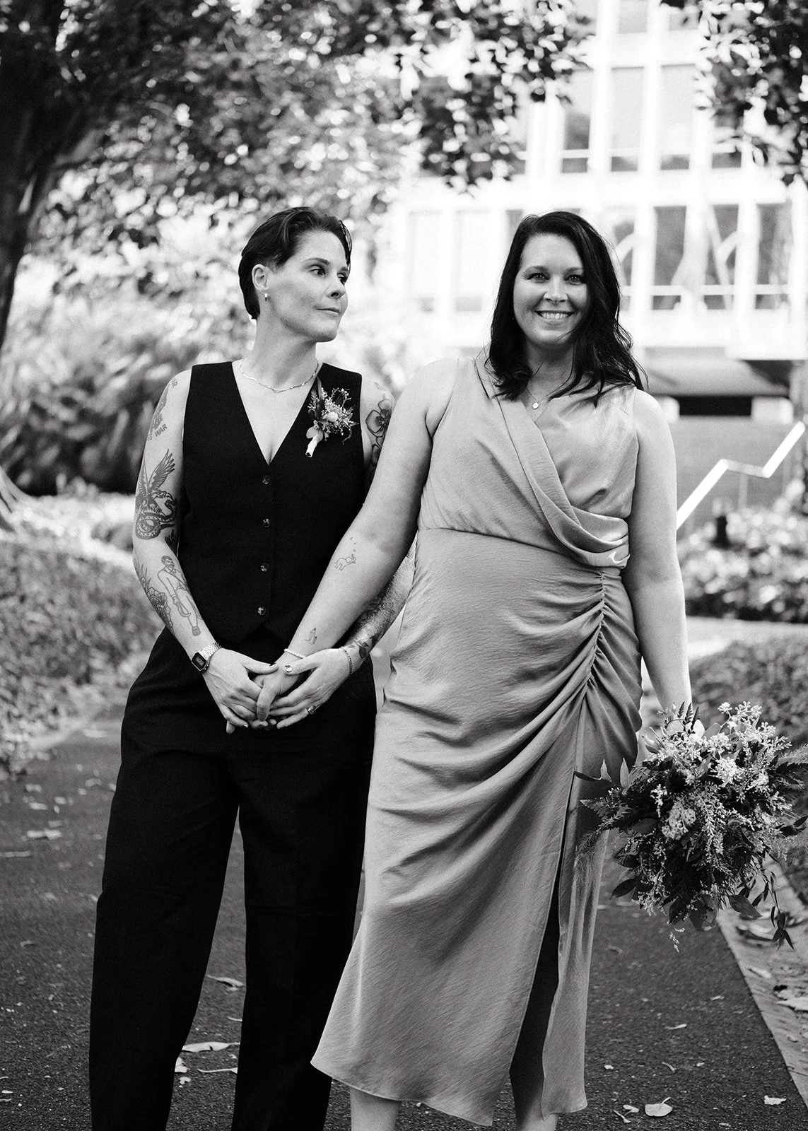 Two brides after their wedding ceremony at the Victorian Marriage Registry. They are standing in Treasury Gardens in Melbourne.