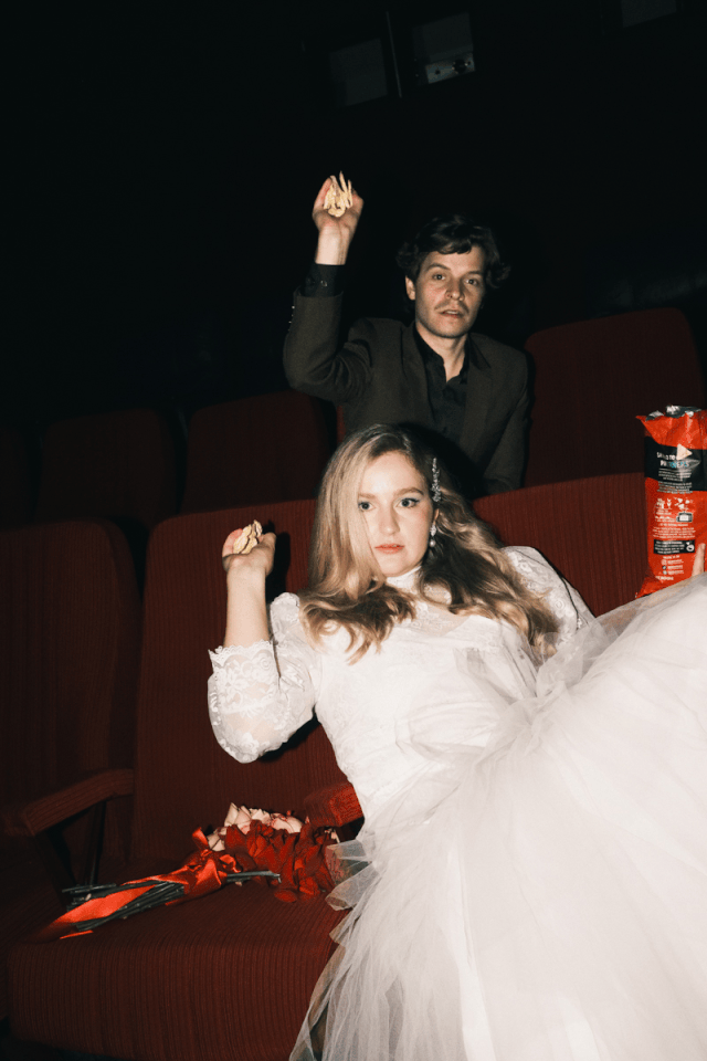 A bride and groom throwing corn chips at the camera before their wedding ceremony