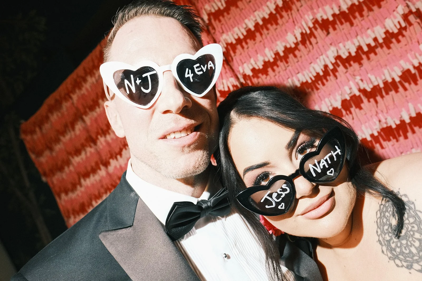 A alternative bride and groom at their wedding at Rupert On Rupert in Collingwood. They're wearing heart-shaped sunglasses with their names on.