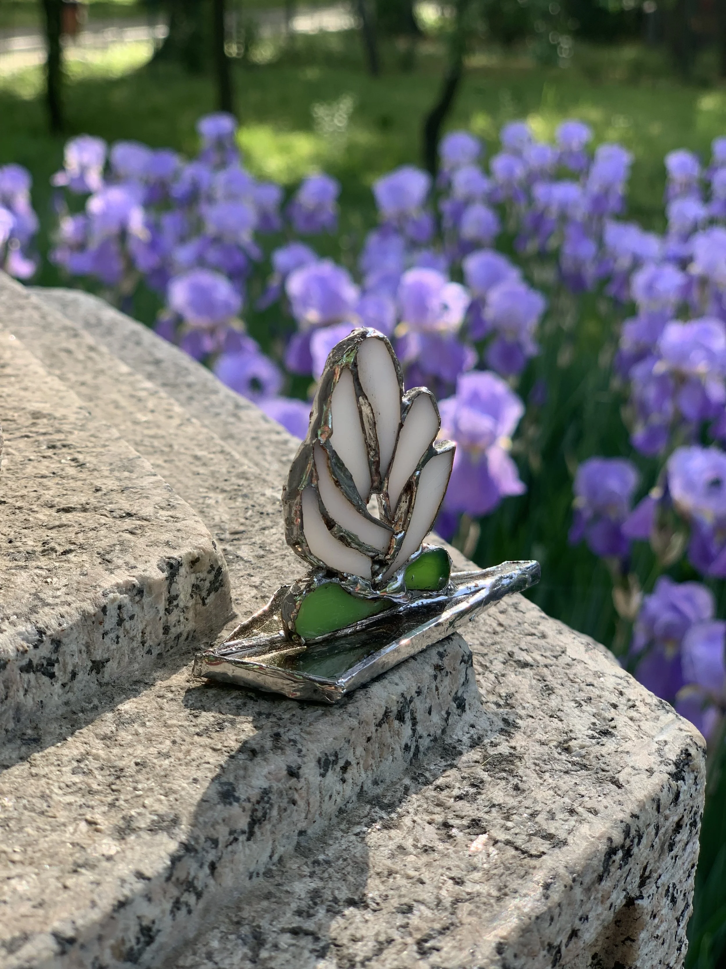 A symbol of enlightenment, a stylized stained-glass lotus on a stone surface with purple flowers in the Japanese Garden