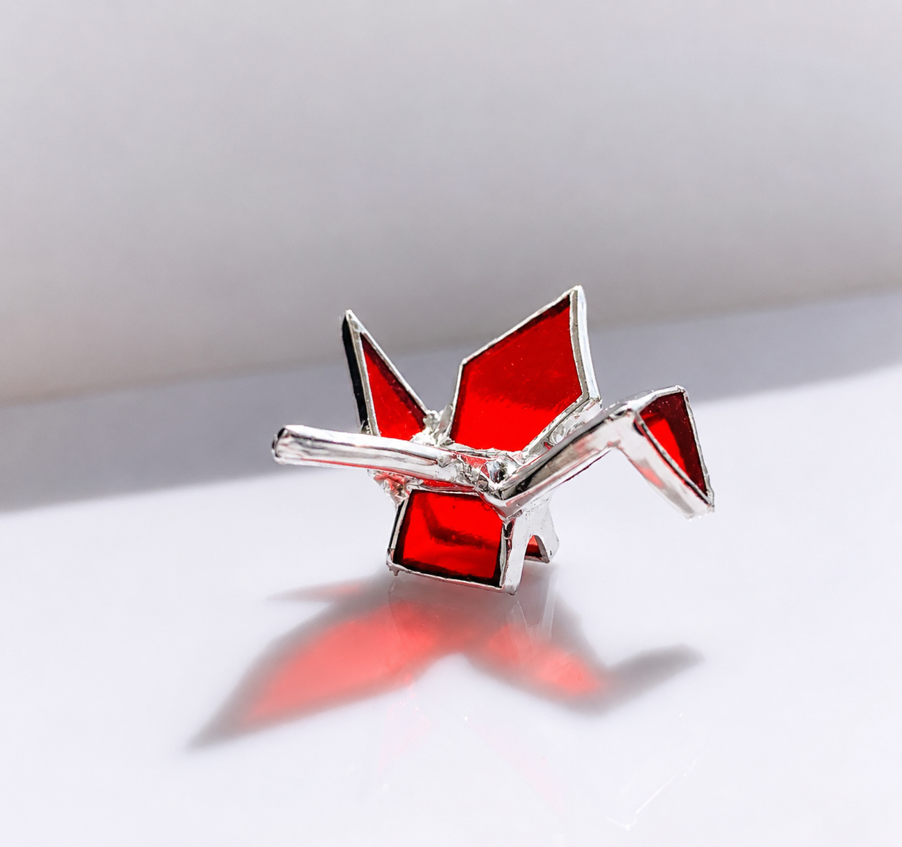 Origami Crane stained glass artwork by Marie ART Gallery, handcrafted from red glass with silver solder lines.