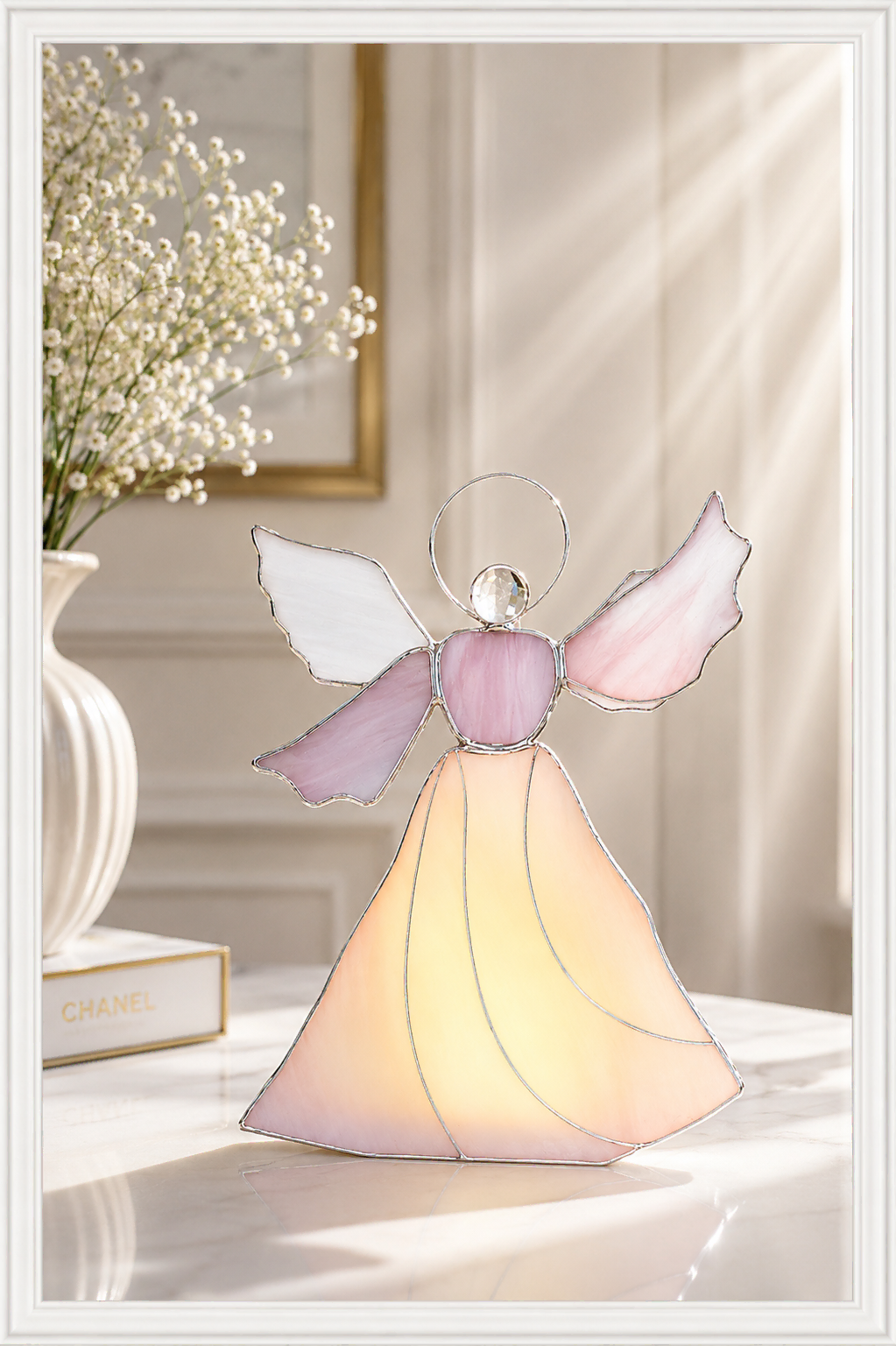 Angel of Light stained glass sculpture by Marie ART Gallery, featuring a luminous angel in soft pink, white, and golden glass, displayed in an elegant sunlit interior.