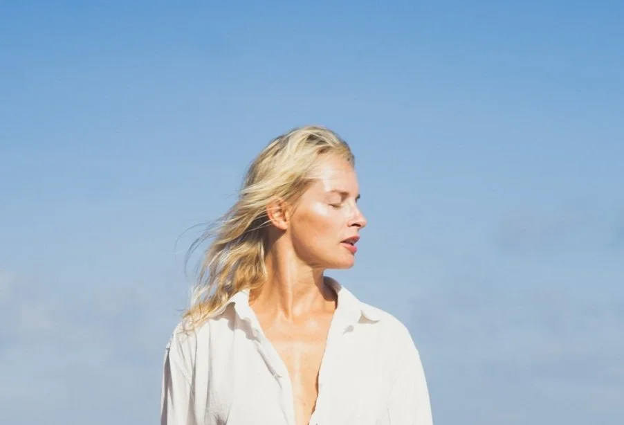 Woman in white shirt against a clear blue sky.