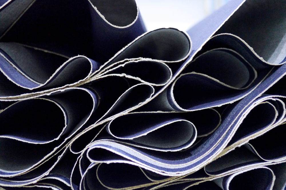 Close-up of rolled fabric swatches with textured edges, arranged in overlapping layers.
