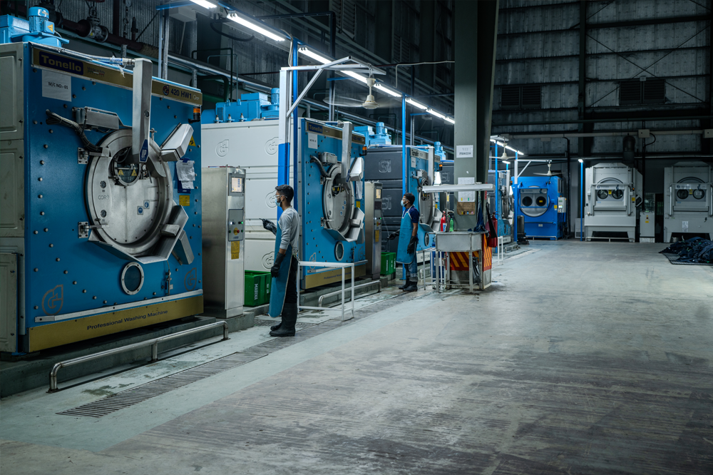 Industrial laundry facility with large washing machines and staff working.