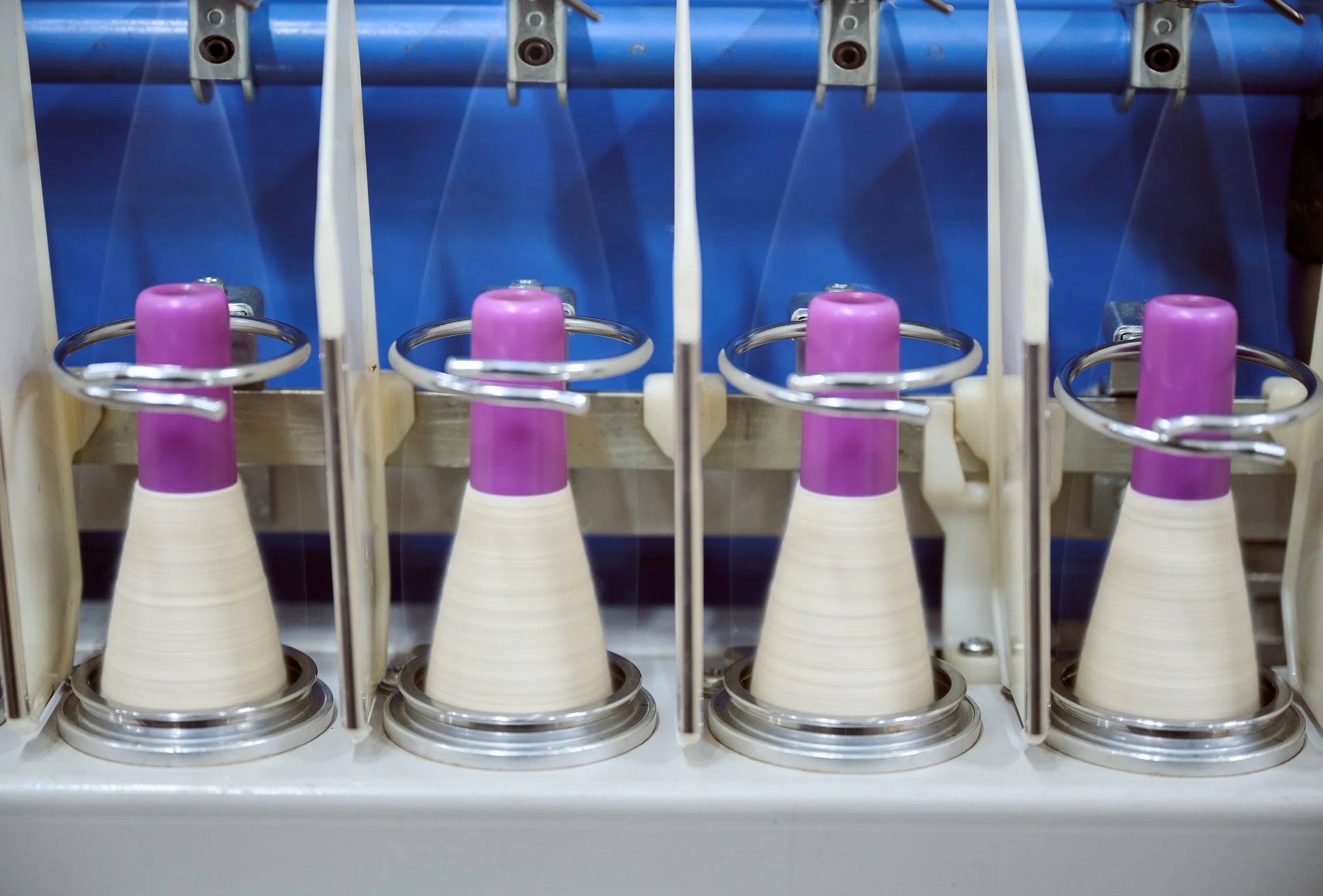 A machine with four purple-capped stacks dispensing white paper cones or cups, arranged in a row inside a dispenser.