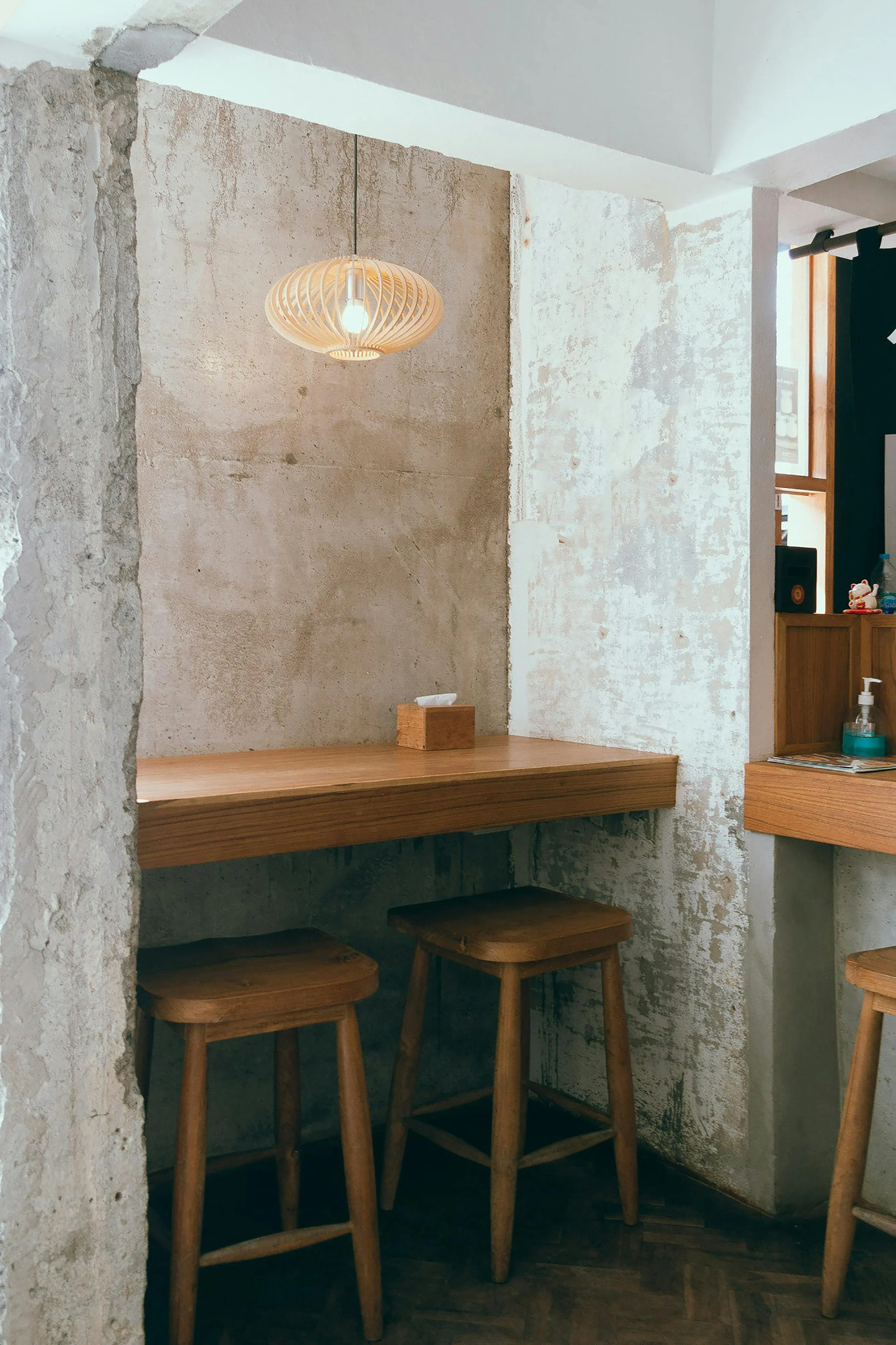 Innenansicht eines Cafés mit Holztischen, Hockern und einer wandähnlichen Zementoberfläche