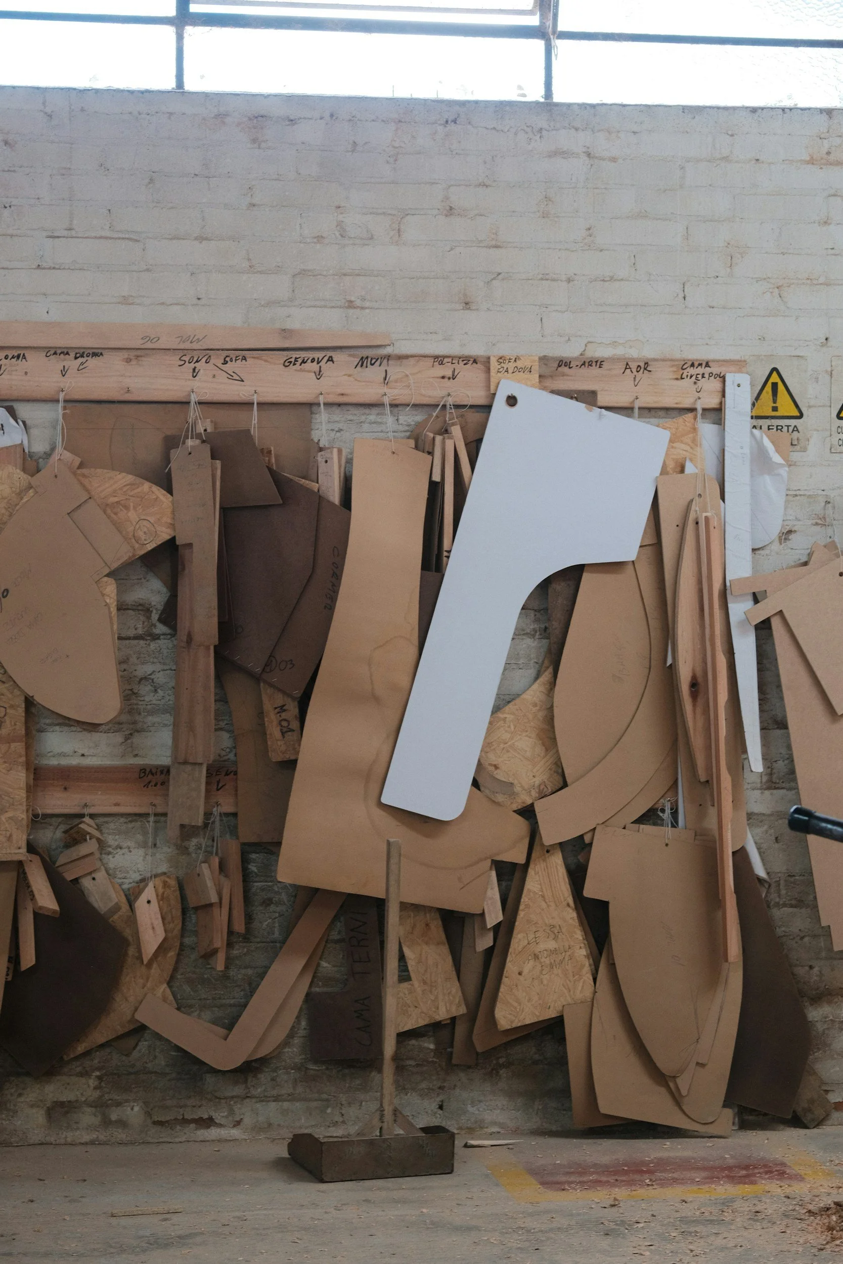 Holzstücke, Zeichnungen und Skizzen an einer Wand im Raum, vermutlich in einer Werkstatt oder einem Atelier.