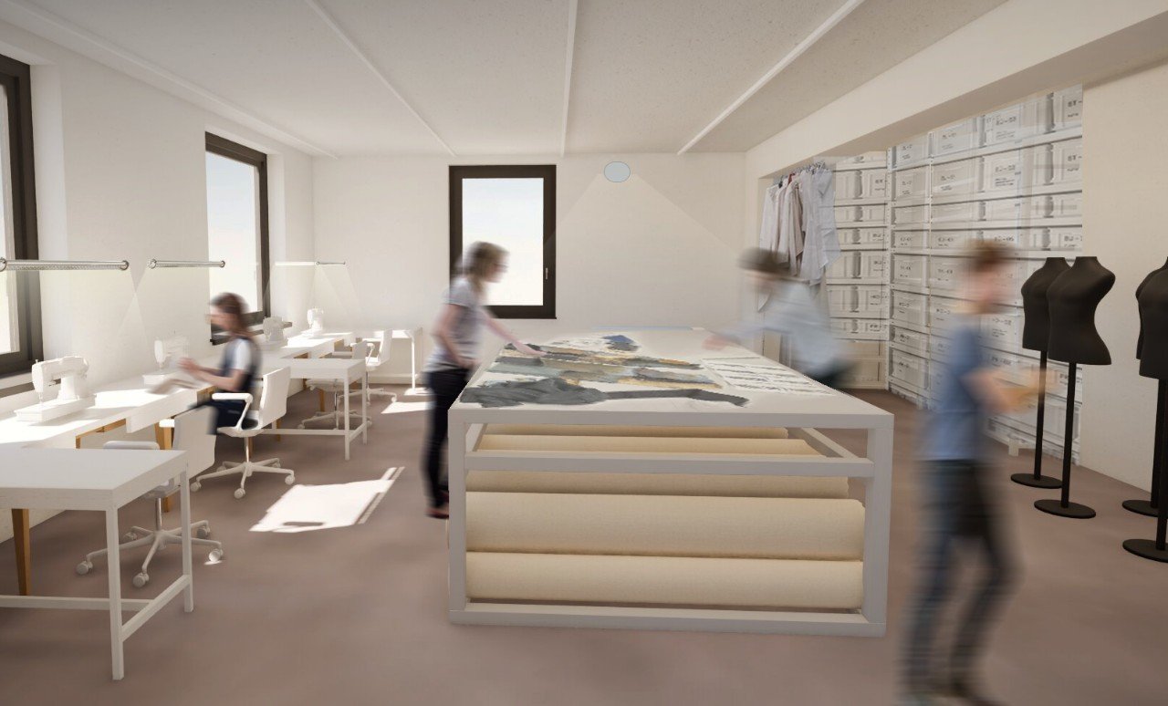 Moderne Designwerkstatt mit weißen Tischen, Nähausrüstung, Stoffproben, Kleidungsstücken und Mannequins in einem hellen Raum mit großen Fenstern.