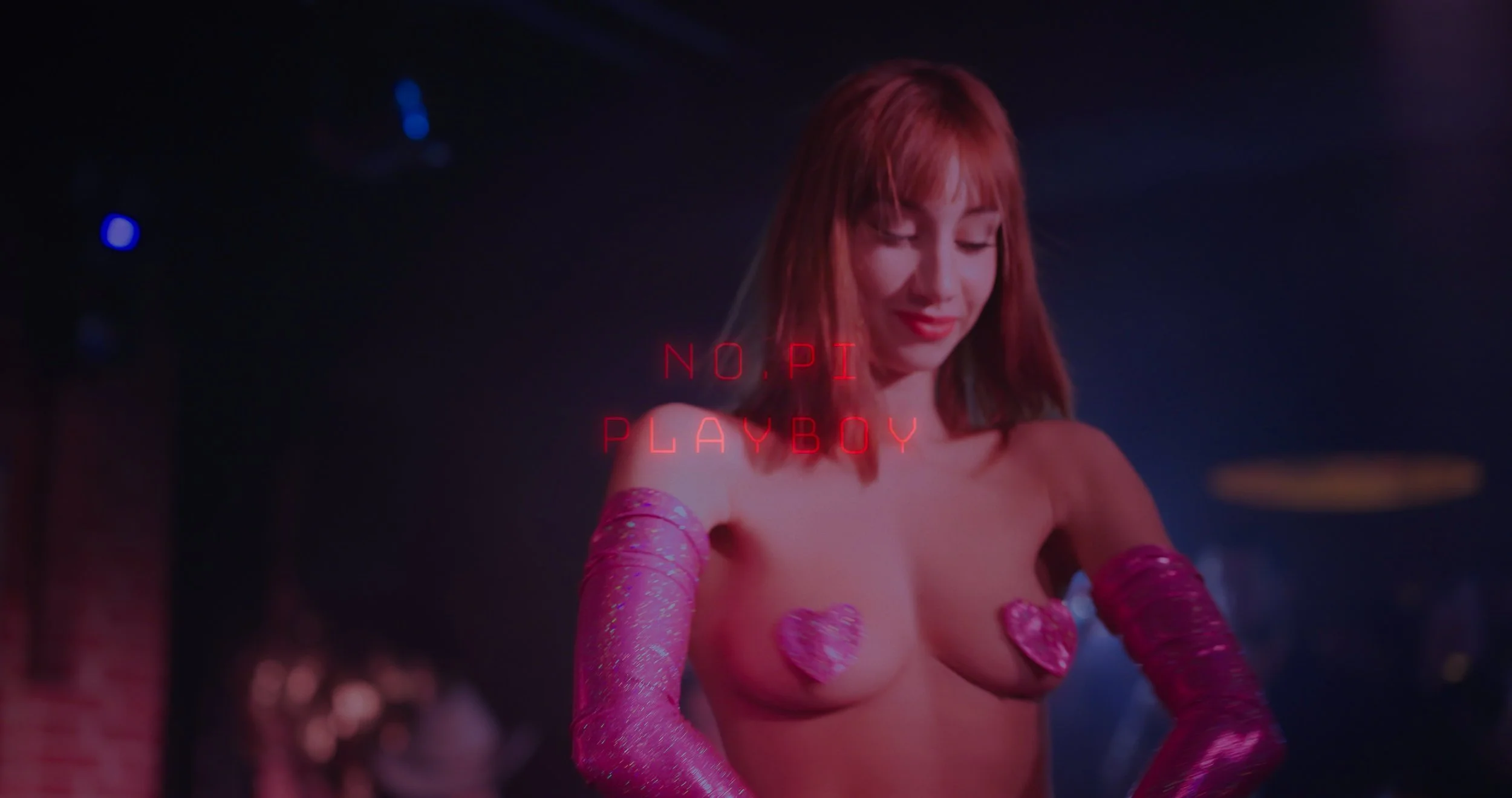 Une femme avec des gants roses, portant des cœurs roses comme cache-tétons, dans une ambiance sombre avec texte rouge "NO PI PLAYBOY" flottant devant elle.