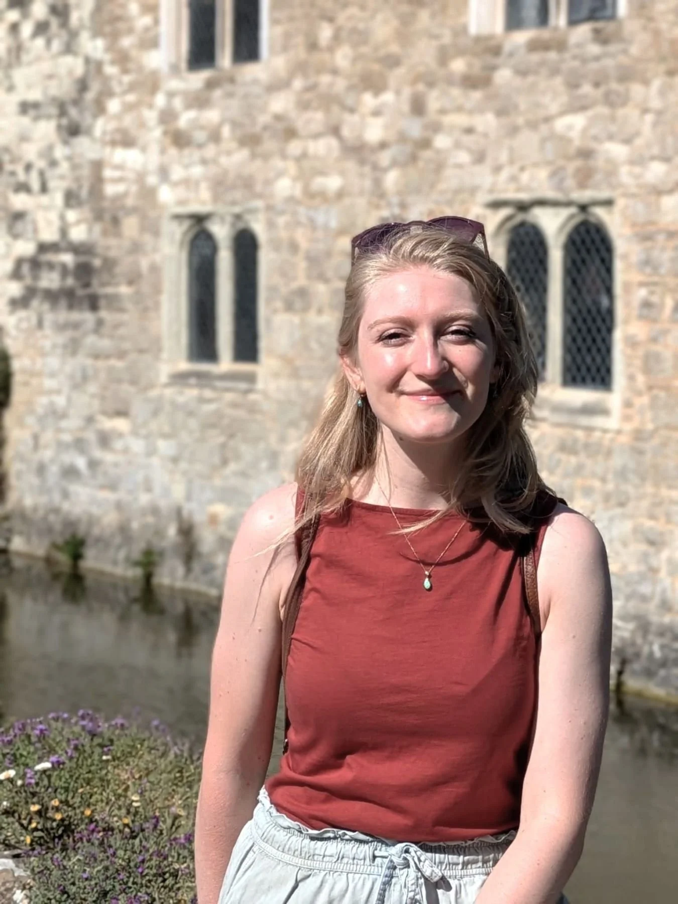 Photo of me - a female heritage and tourism writer with blonde hair - in front of a medieval building.