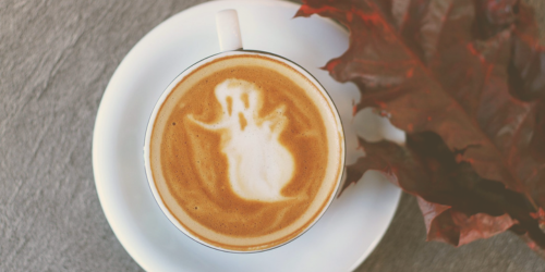 Photo of a mug of coffee with a ghost shape created in froth on the surface.