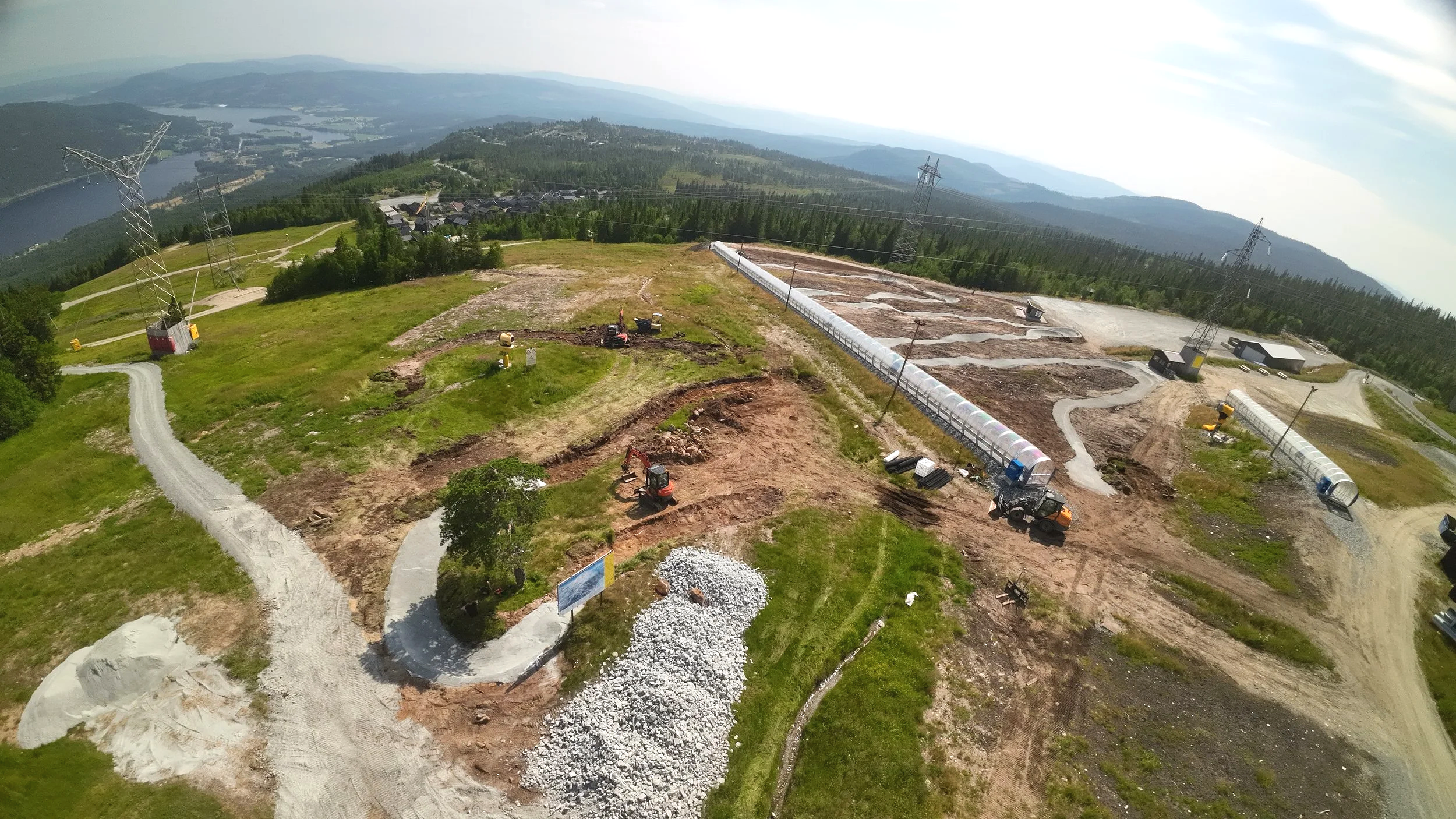 Gravemaskin og trailbyggere arbeider med terrengforming på Norefjell.