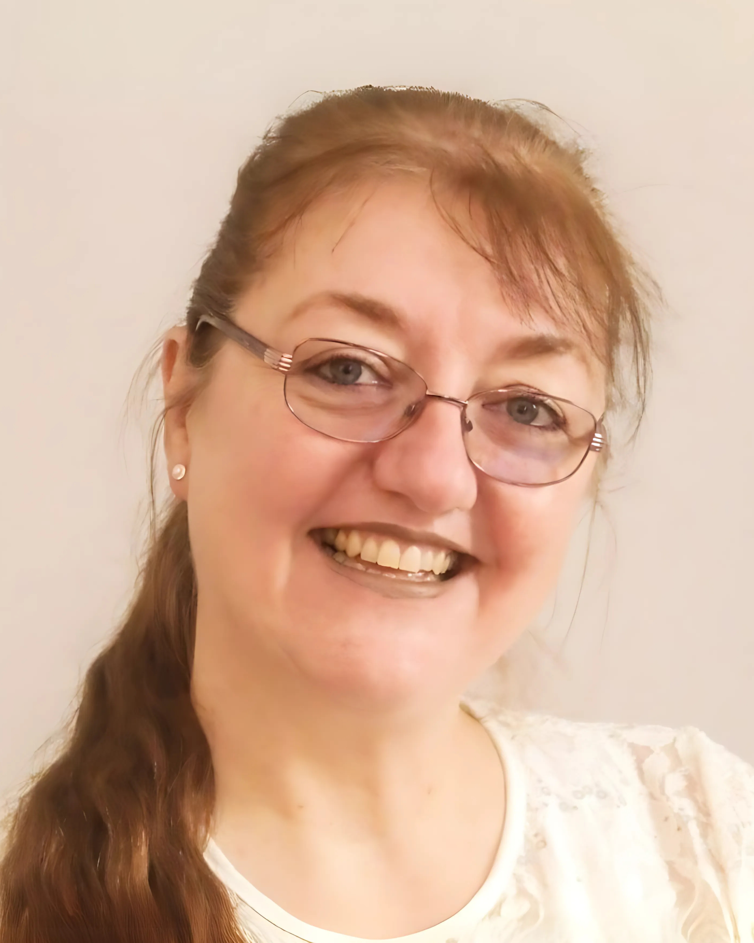 A woman with glasses and long reddish hair smiling at the camera.