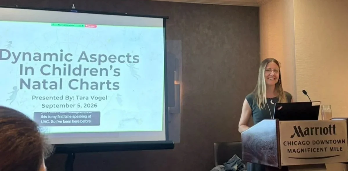Tara Vogel presenting Dynamic Aspects in Children's Natal Charts from a podium with slides on sceen