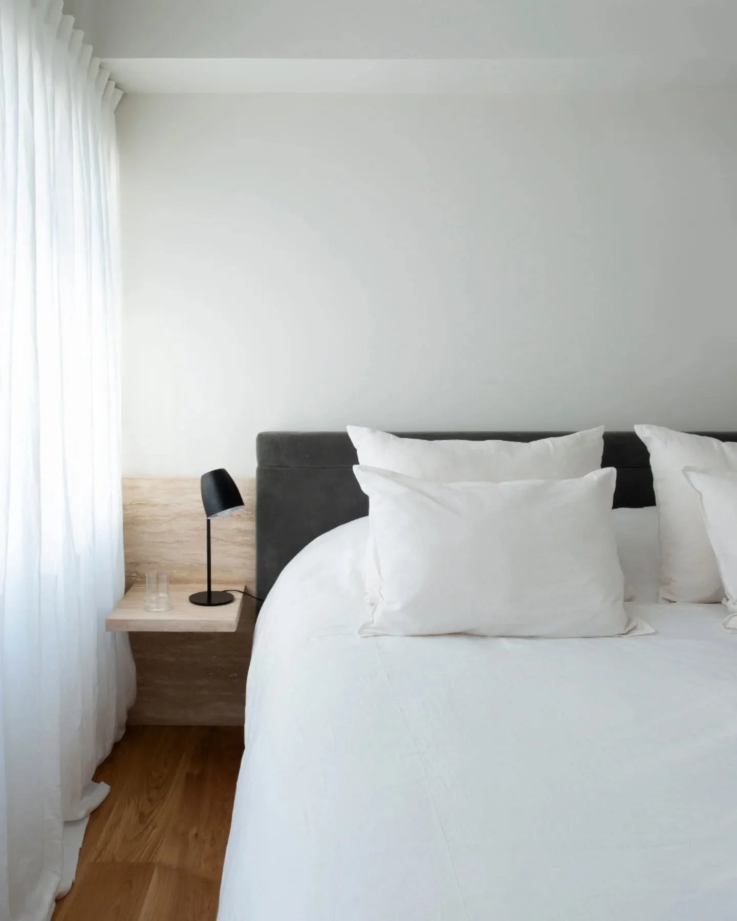 Una habitaci&oacute;n pensada desde la calma. 
La cama, se apoya sobre un respaldo en travertino y pana gris topo que define el eje del espacio. 

El mueble de madera natural integra la tv sin interrumpir la continuidad del ambiente, reforzada por el