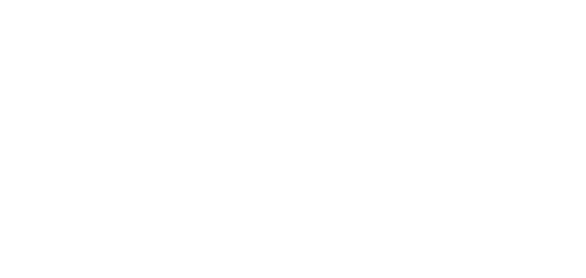 A hairless dog, possibly a Chinese Crested, sitting on a wooden surface with a green leafy background.