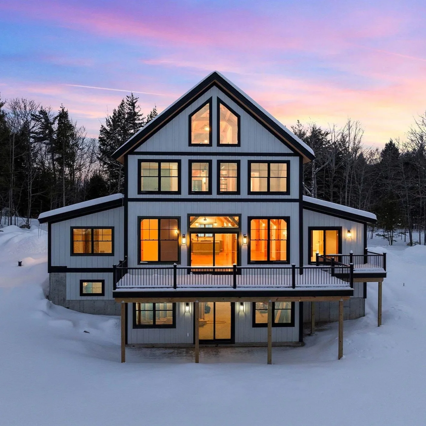 Modern cabin in snowy landscape at sunset