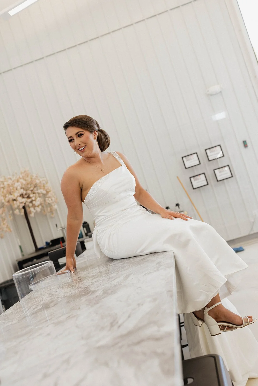 The bride sits on top of the bar at the PBC Venue.