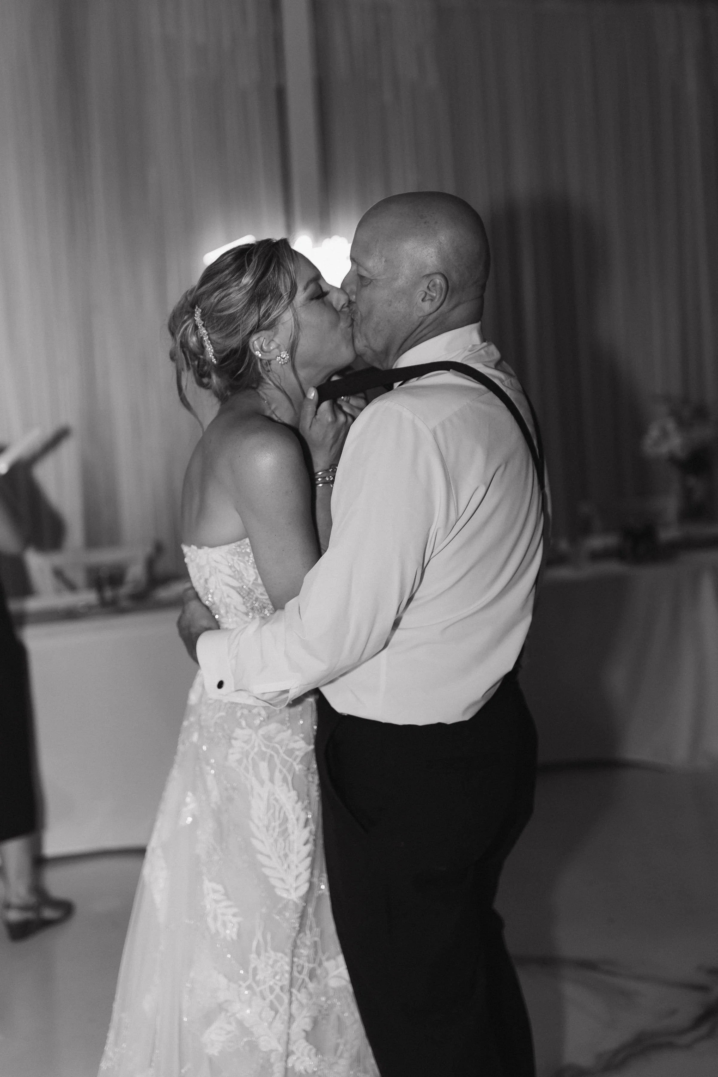 A bride and groom sharing a kiss during their wedding dance in a reception hall.