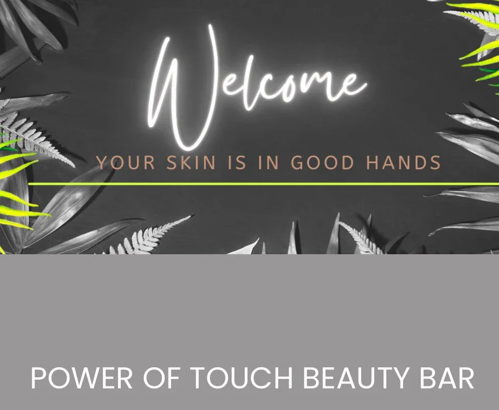 A sign with a dark background and decorative leaves around the edges. The sign reads "Welcome" in cursive, with the subtext "Your skin is in good hands" and a line separating the text from the bottom. At the bottom, it says "Power of Touch Beauty Bar".