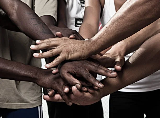 Multiple hands of diverse people stacked together in a symbol of unity and teamwork.