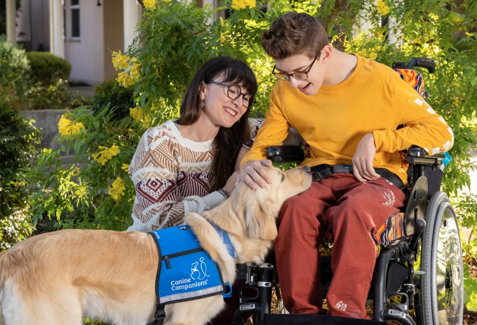 Boy in wheelchair with caregiver and service dog