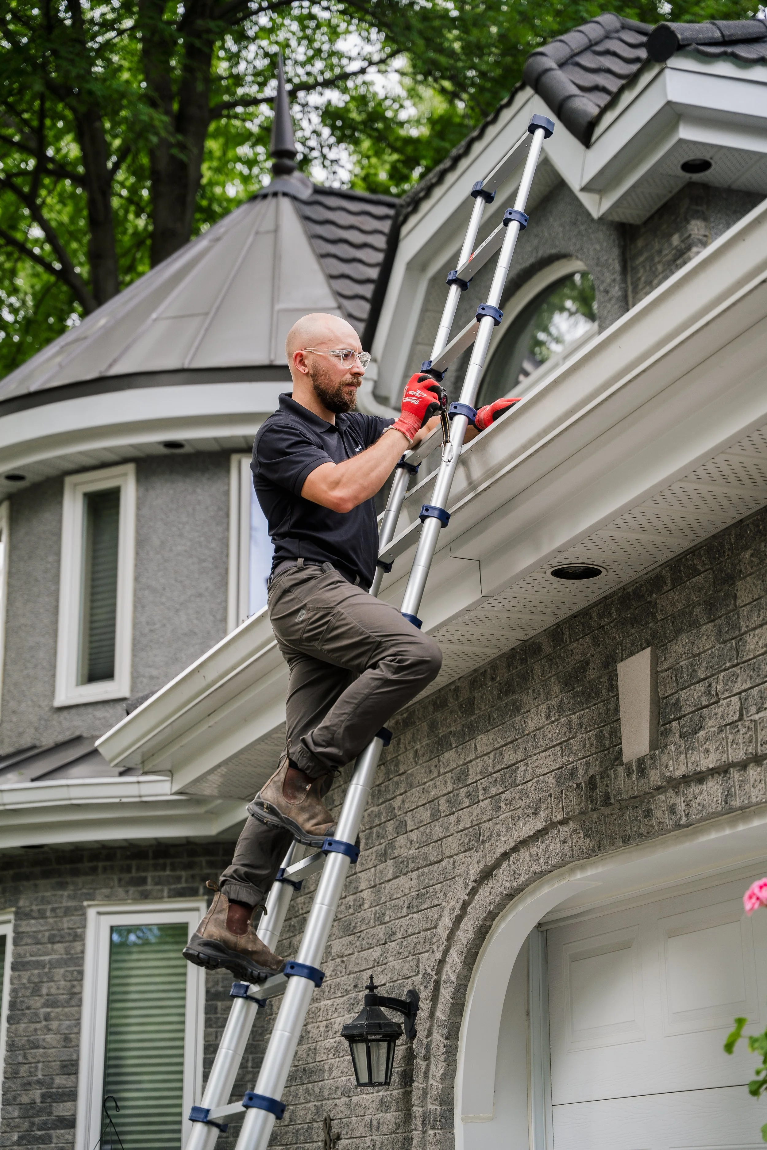Un homme utilisant une échelle pour effectuer des travaux sur la façade d'une maison en pierre