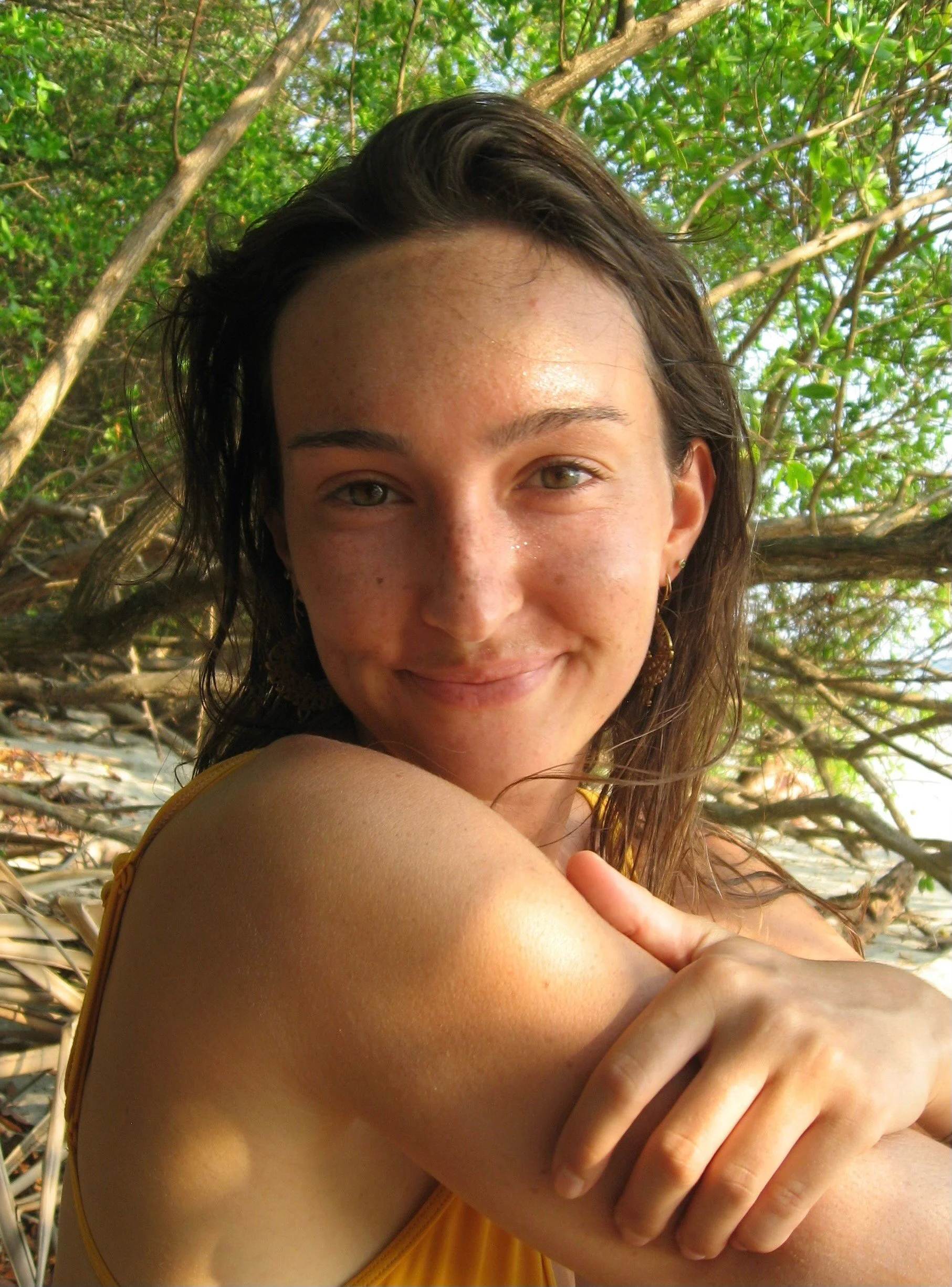 Sunny brunette woman smiles as she is sitting by a river