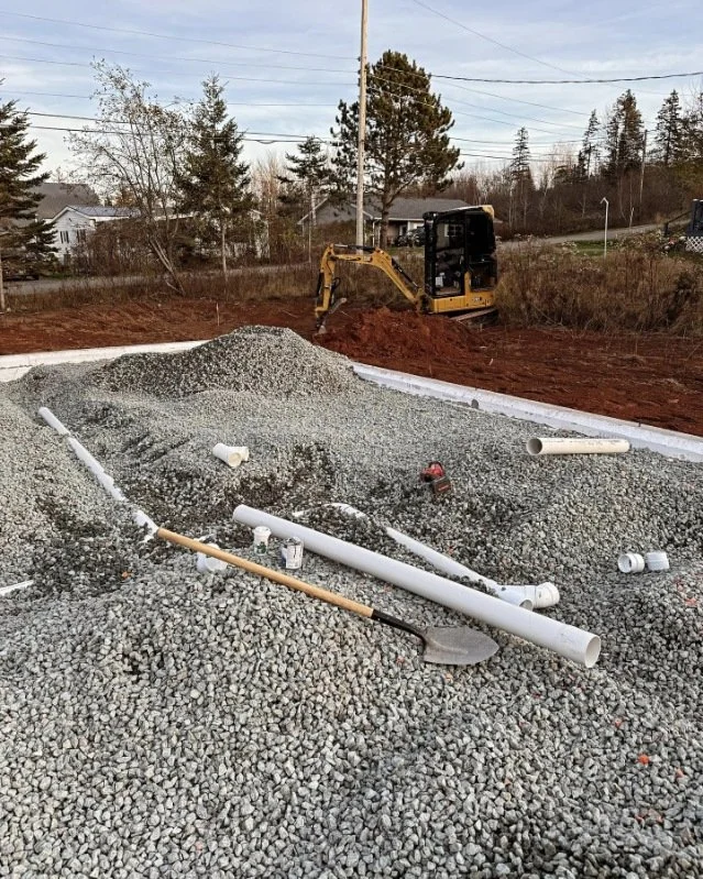 Construction site with gravel, PVC pipes, and a mini excavator