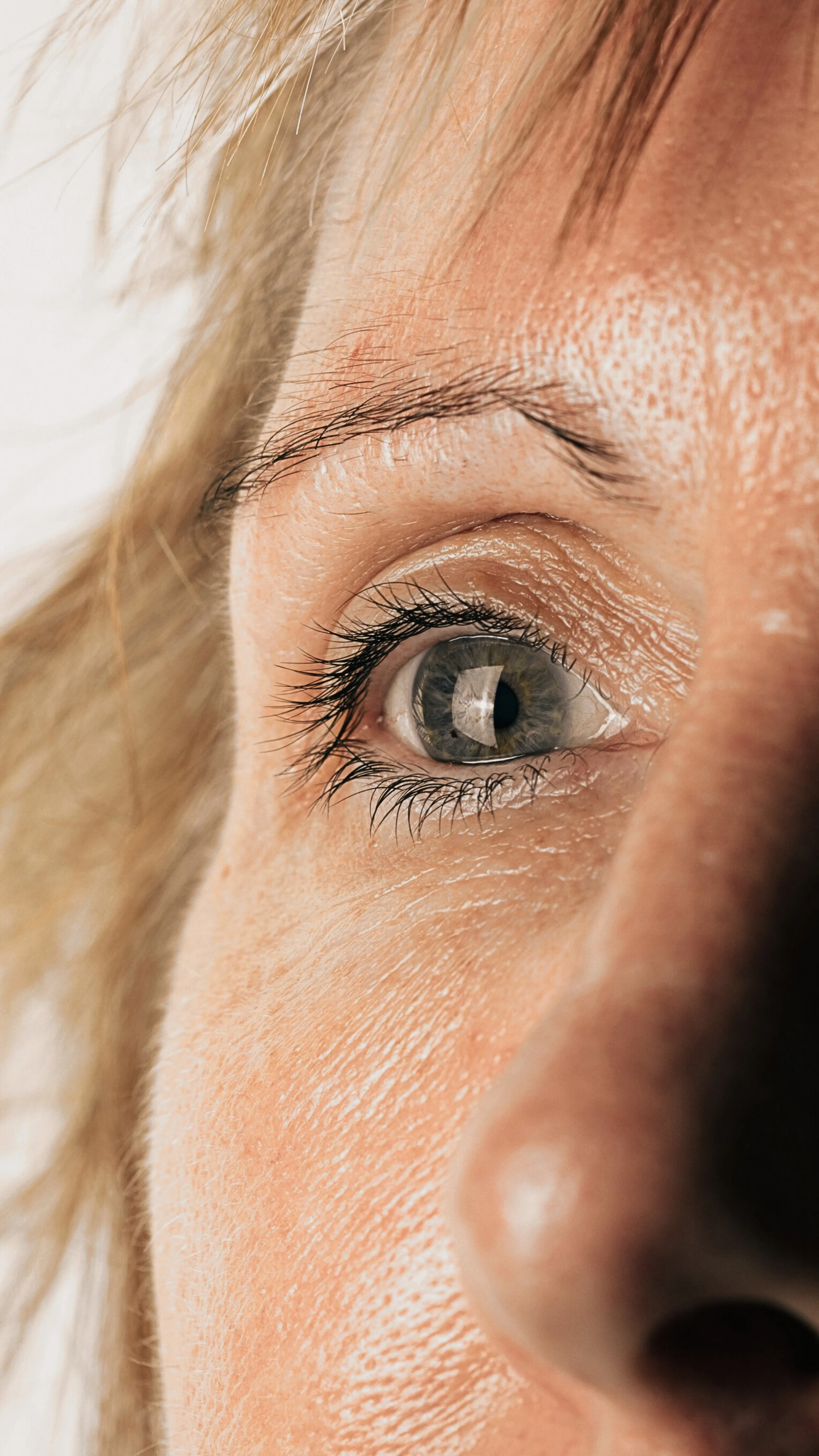 Close-up of a person's right eye, showing the sclera, iris, and eyelashes. The person has light skin and blonde hair.
