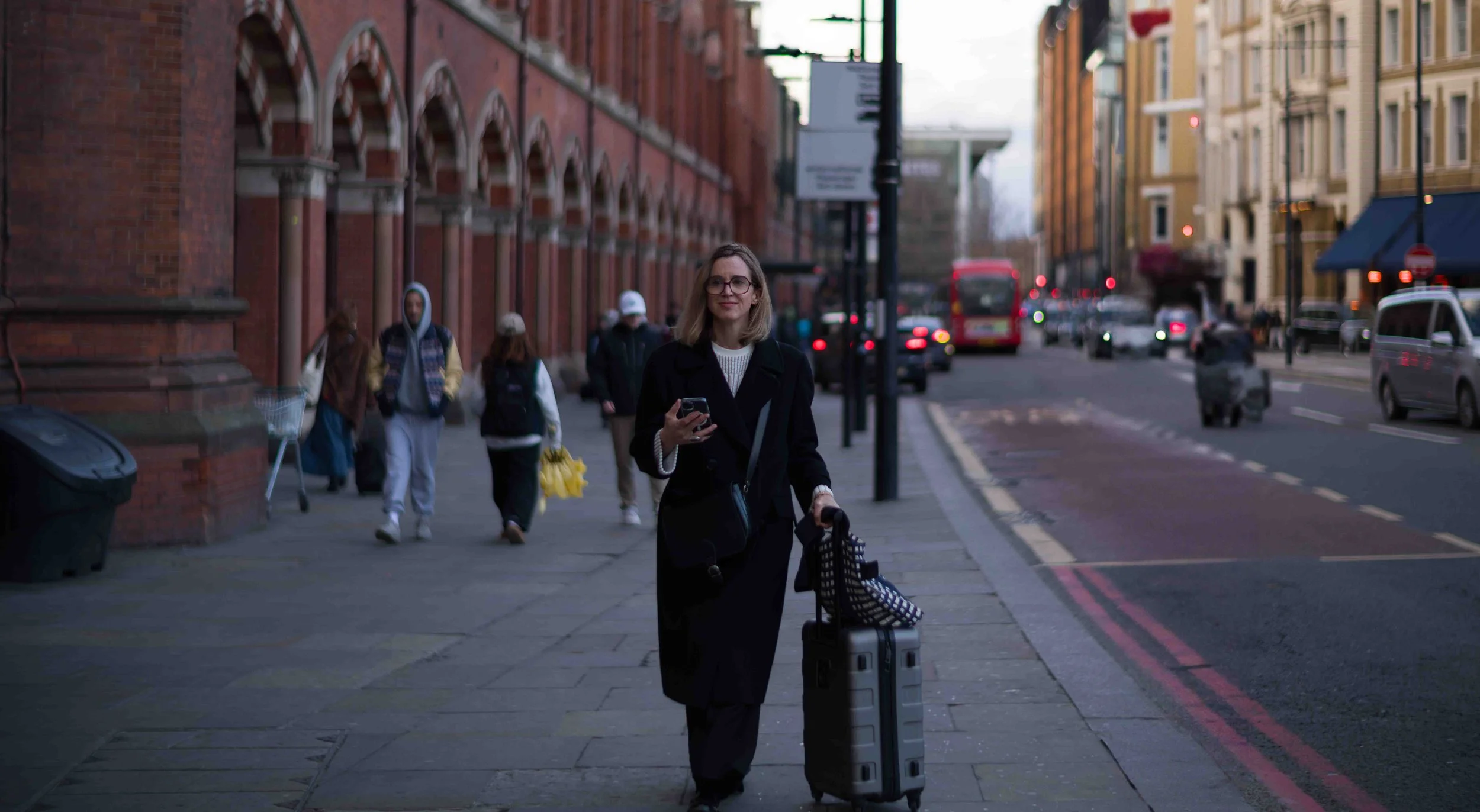 The wheels of her suitcase hummed softly against the pavement, a familiar sound in a city that thrives on transit. She had just stepped out of the station, the rush of train arrivals and departures fading behind her. The air carried the scent of coff