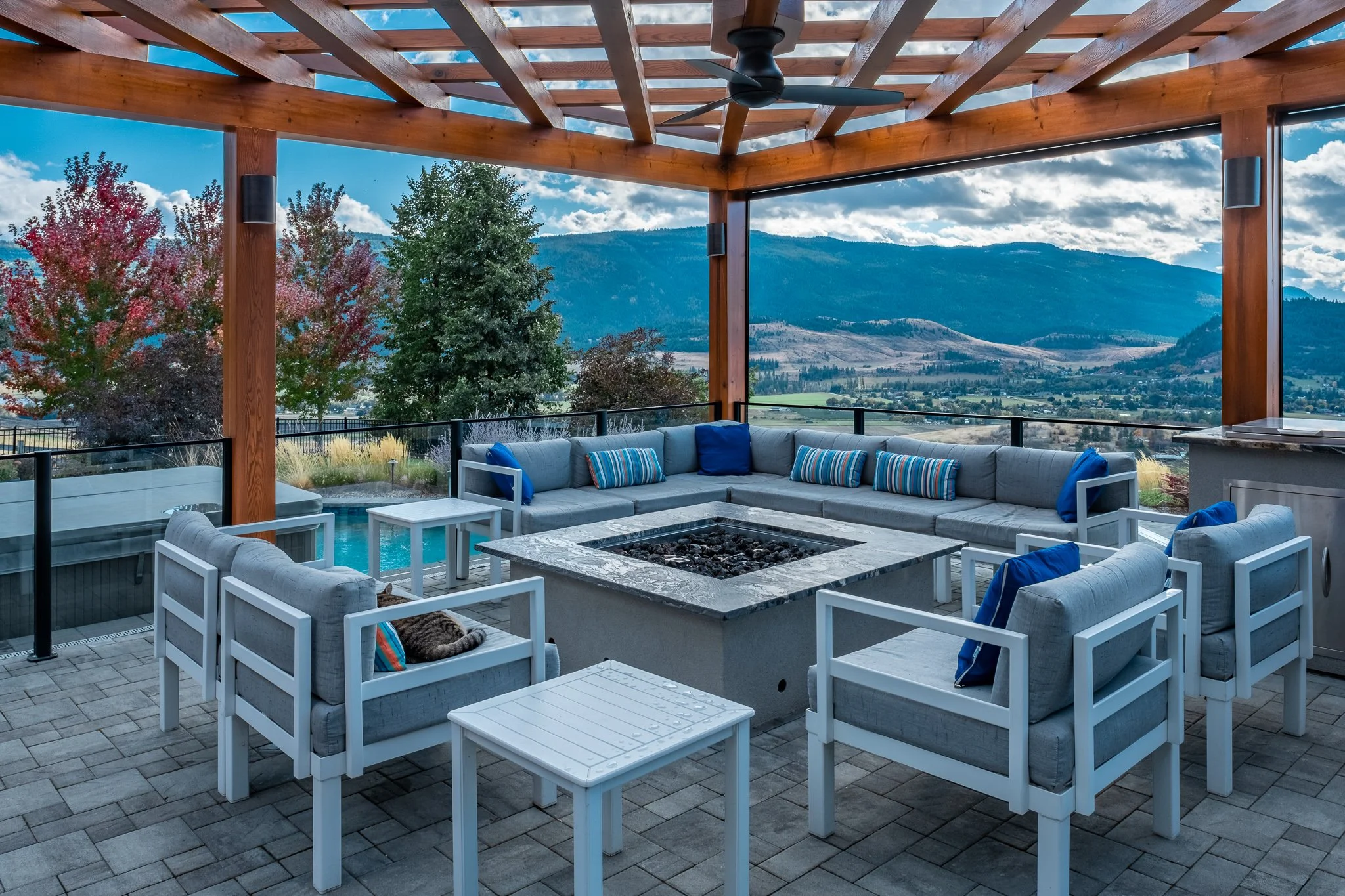 Outdoor patio with pergola, sectional seating, fire pit, scenic mountain view, and colorful fall trees.