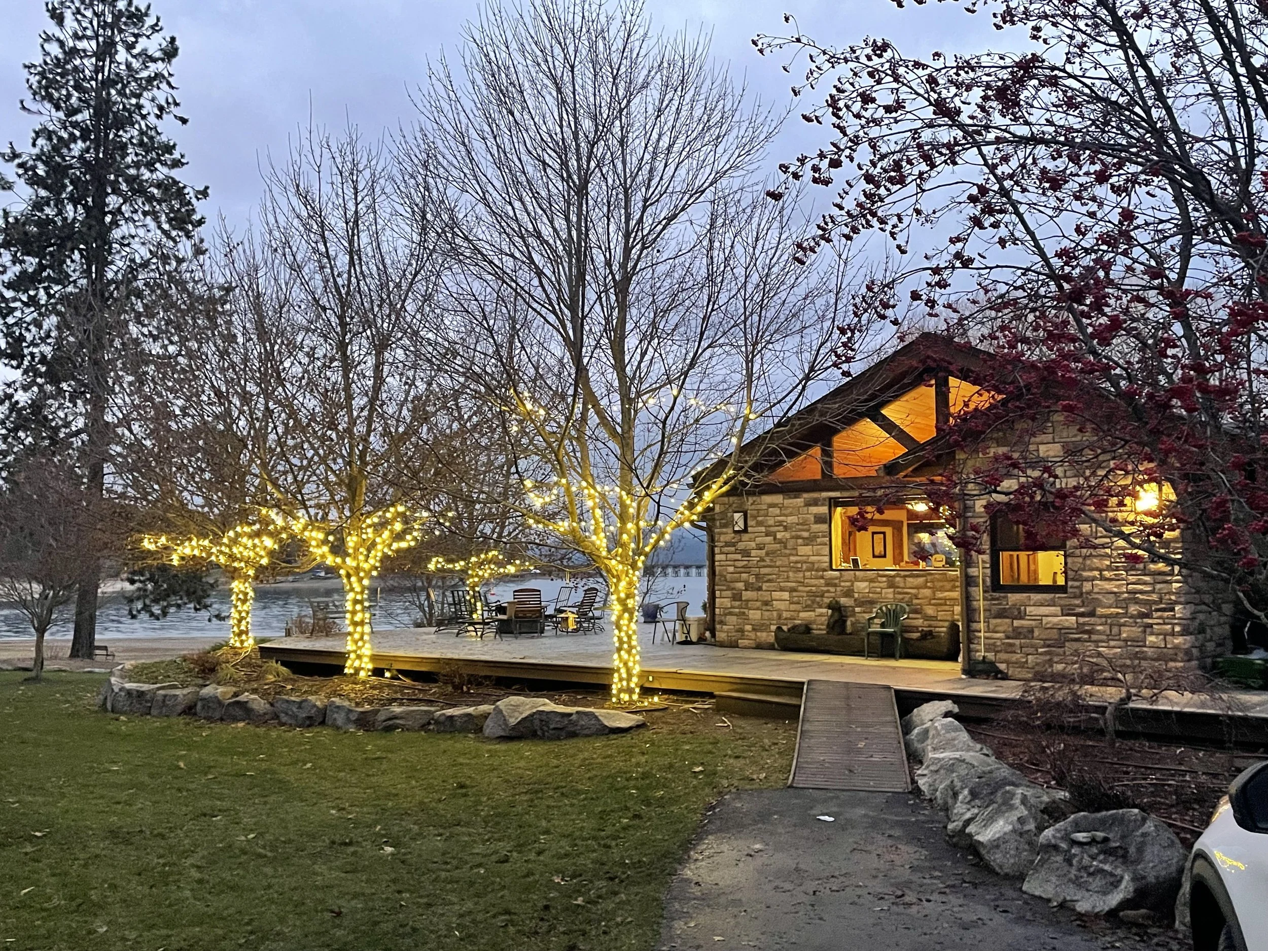 Cozy stone cabin with illuminated trees on a lakeside in the evening