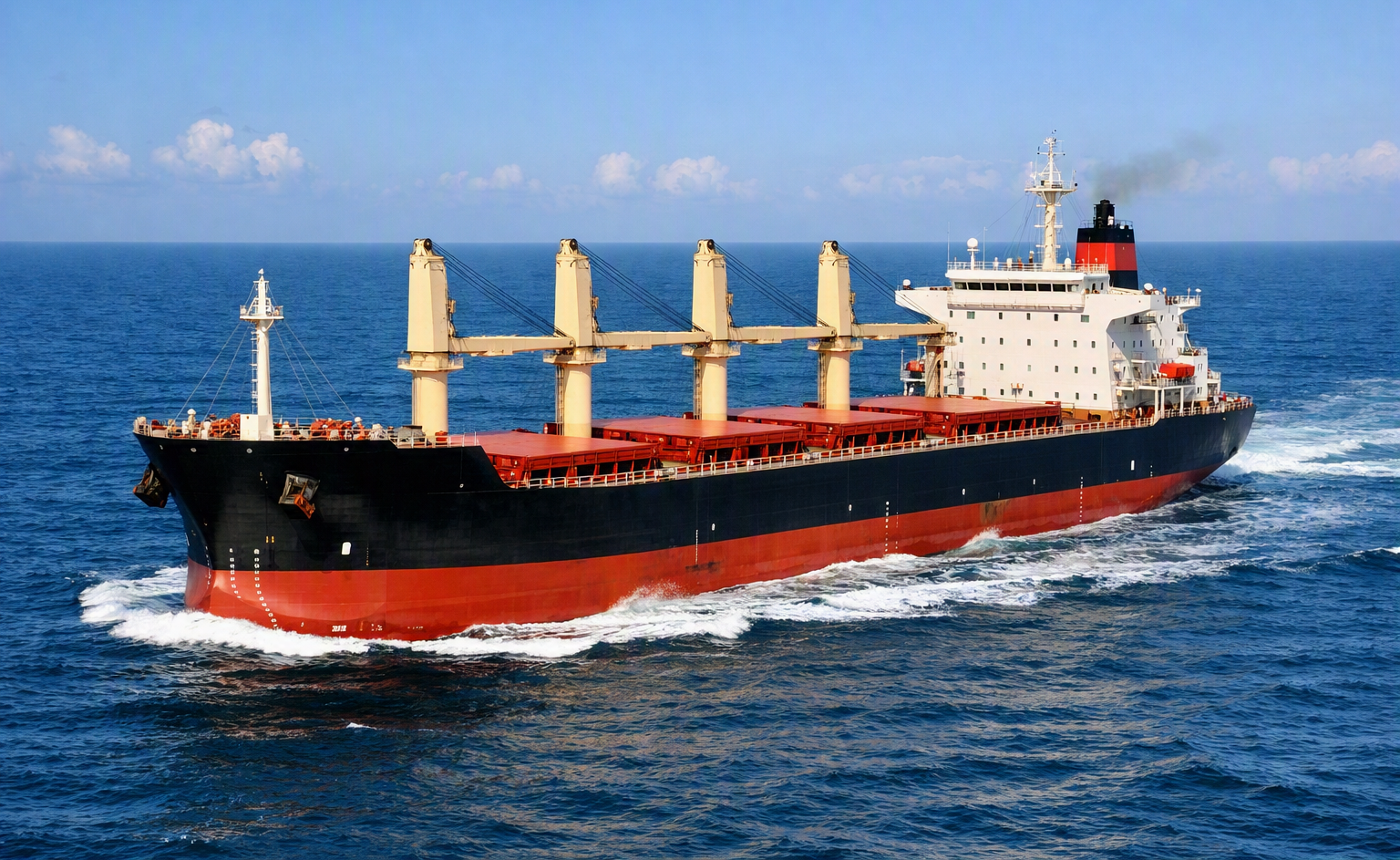 A large cargo ship sailing on the ocean with a clear sky in the background.