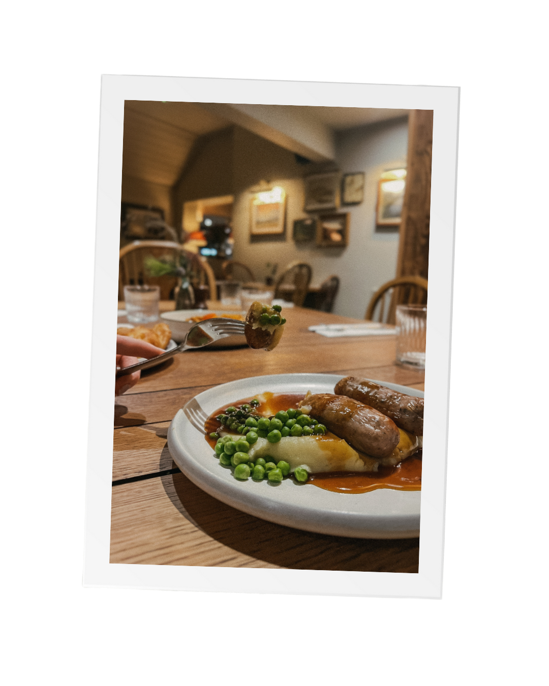 An image of a small portion of sausage, mash and peas on a wooden table for the kids meal for £5 in February as a special offer for families at a local Sussex pub, The Thatched Inn.