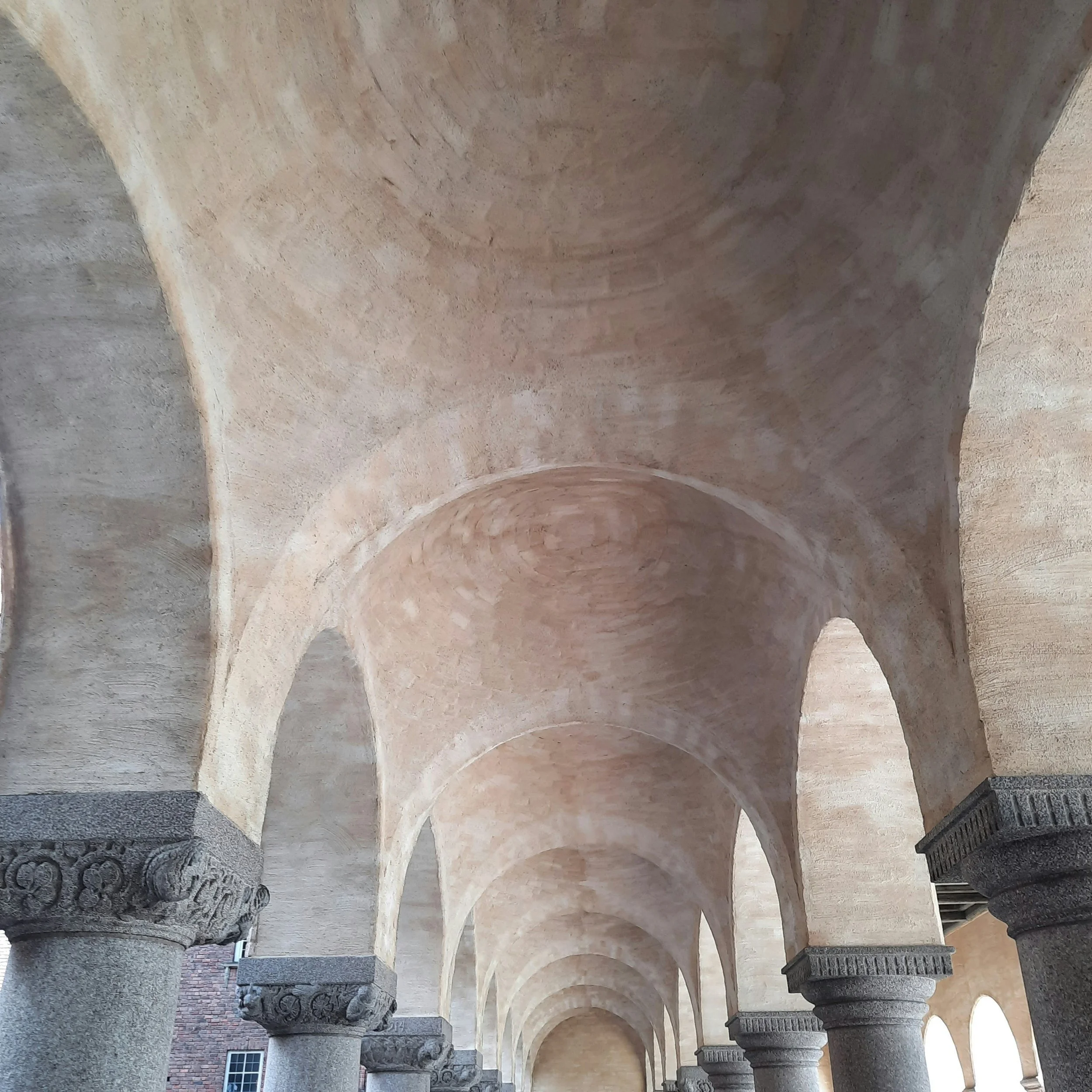 Archway corridor with stone columns and vaulted ceilings.