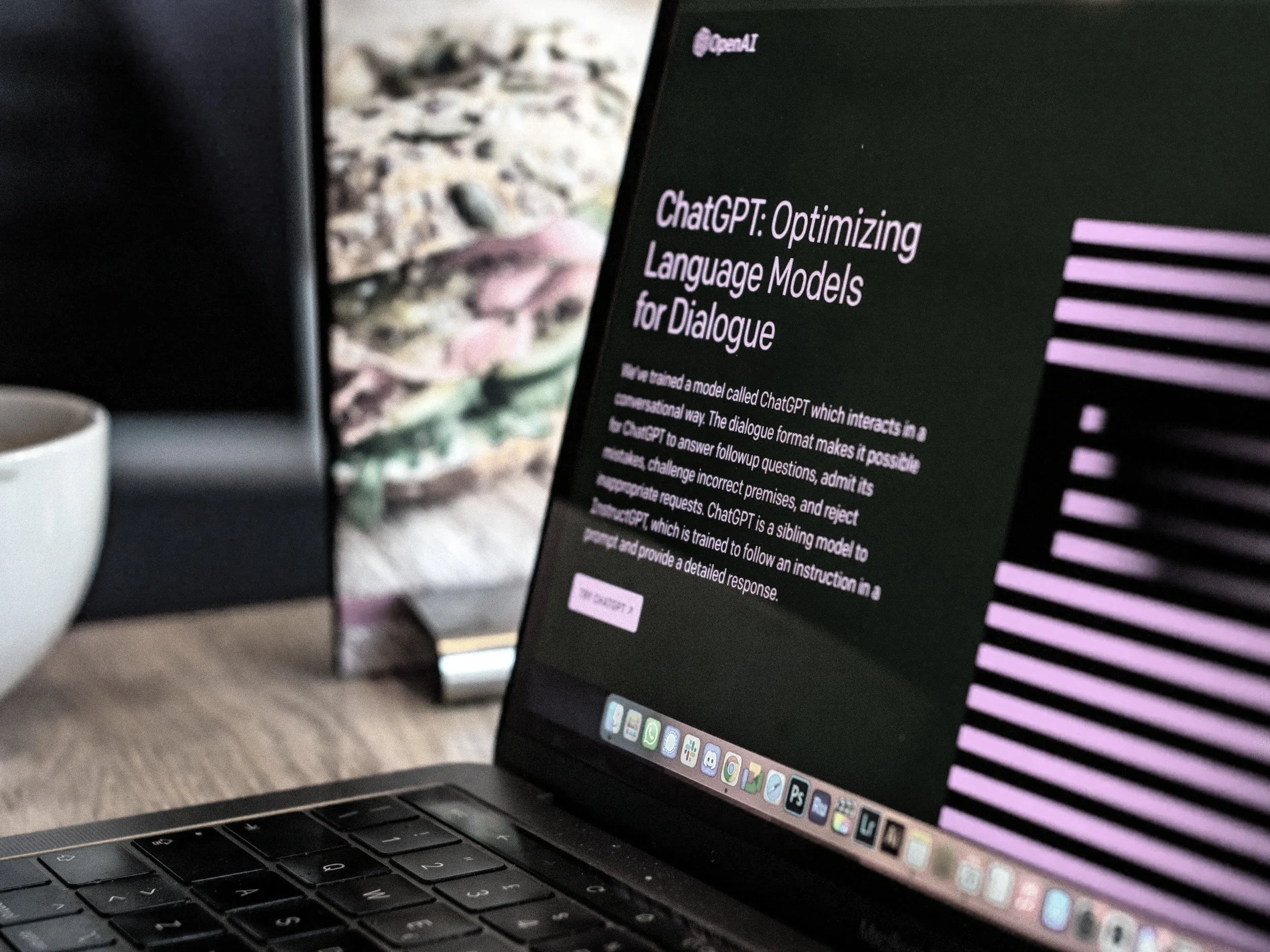 Laptop displaying a presentation about ChatGPT and language models for dialogue, with a book and a coffee mug on a wooden table in the background.