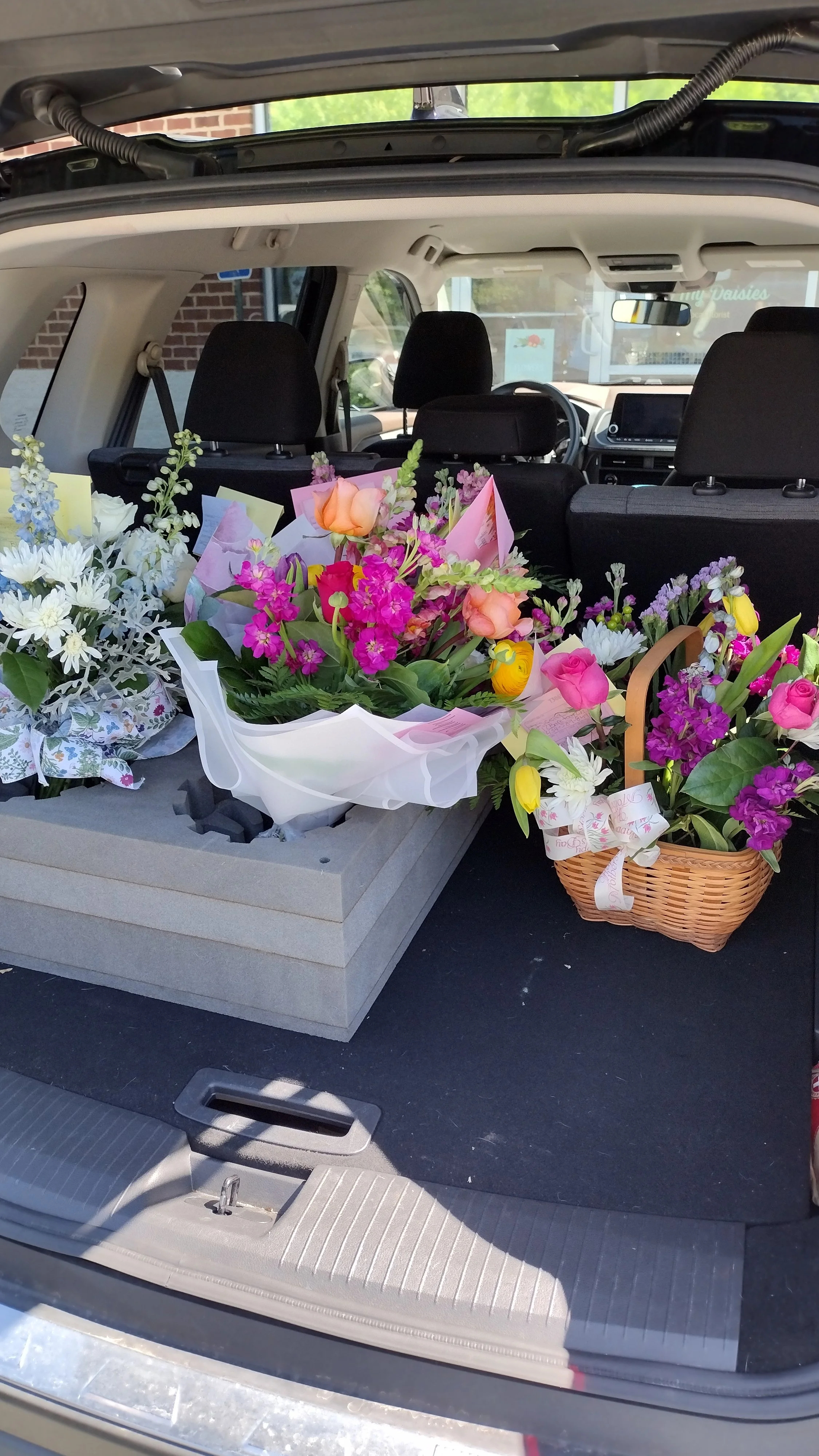 The back of an SUV loaded with colorful flower bouquets and baskets.