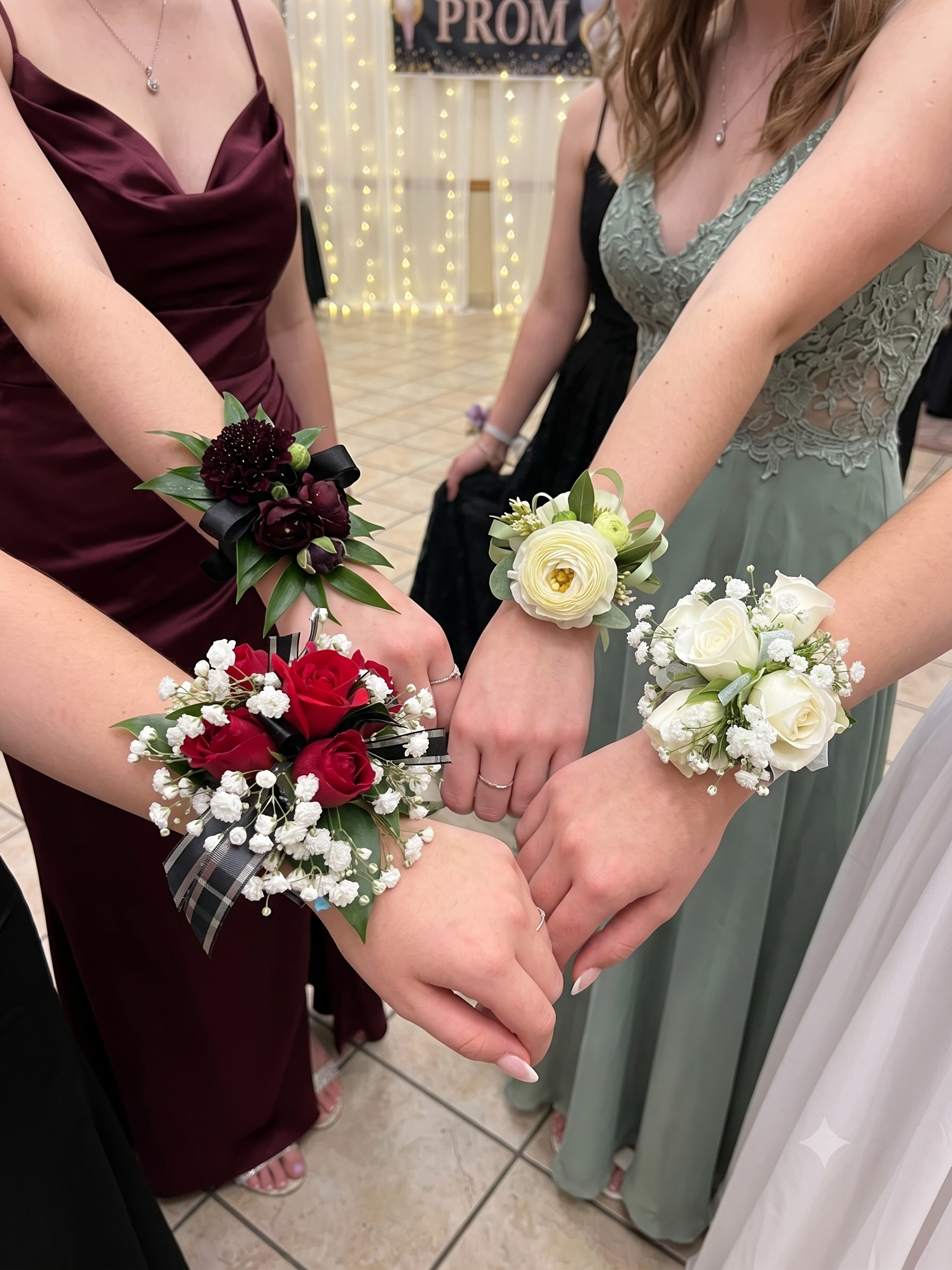 People are holding hands with corsages on their wrists at a prom event.