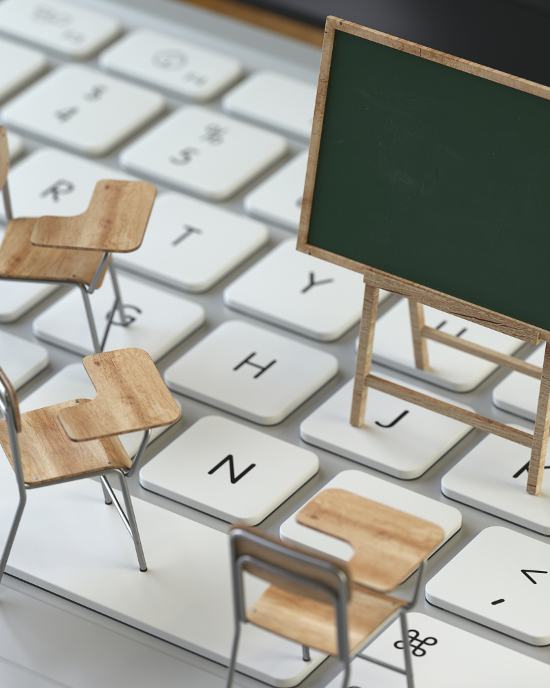 Miniaturas de pupitres y pizarra en una superficie de teclado de computadora.