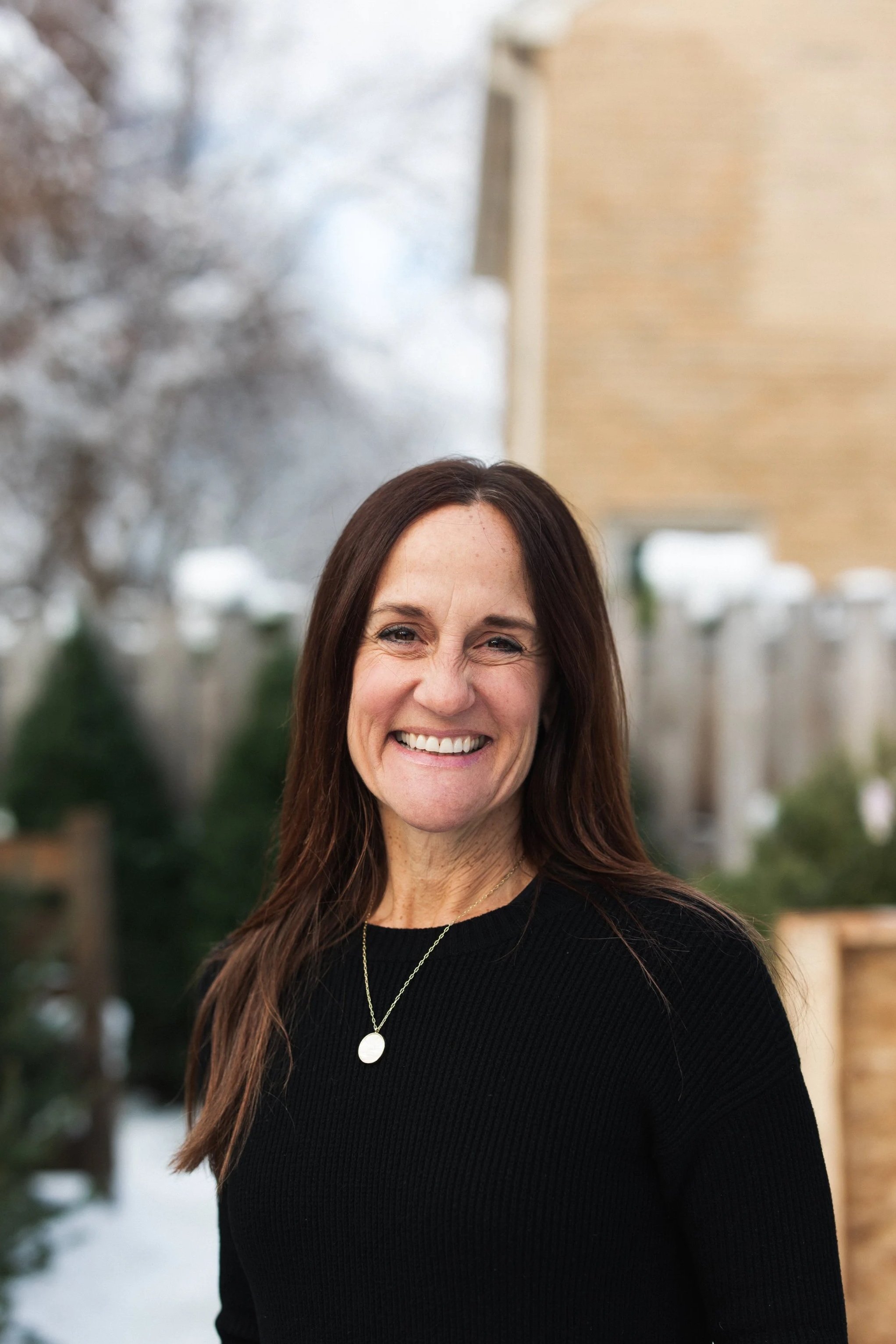 Home organizer Beth standing in a room with organized cabinets and smiling